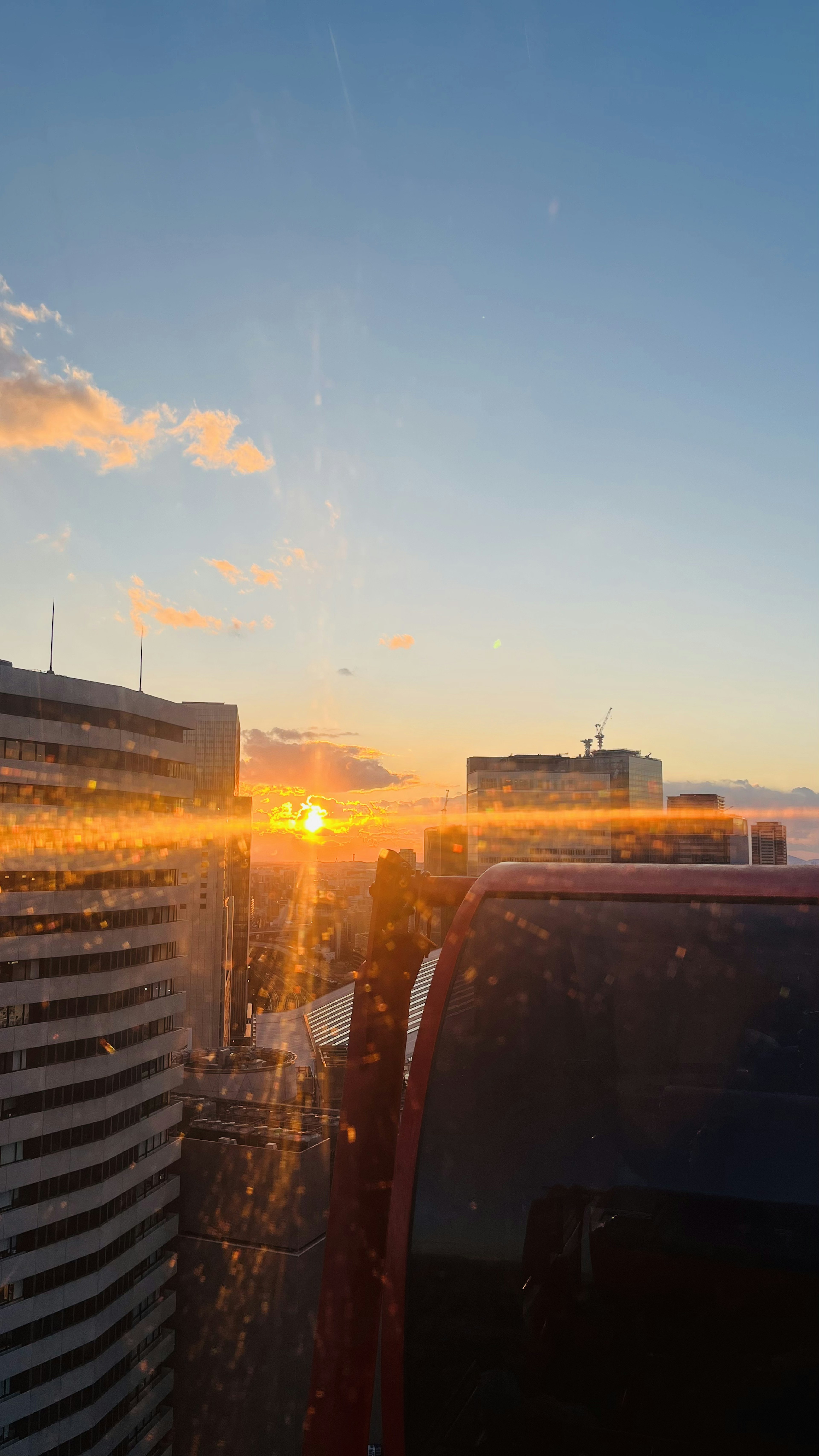 Vue depuis un toit montrant le reflet du coucher de soleil avec des bâtiments