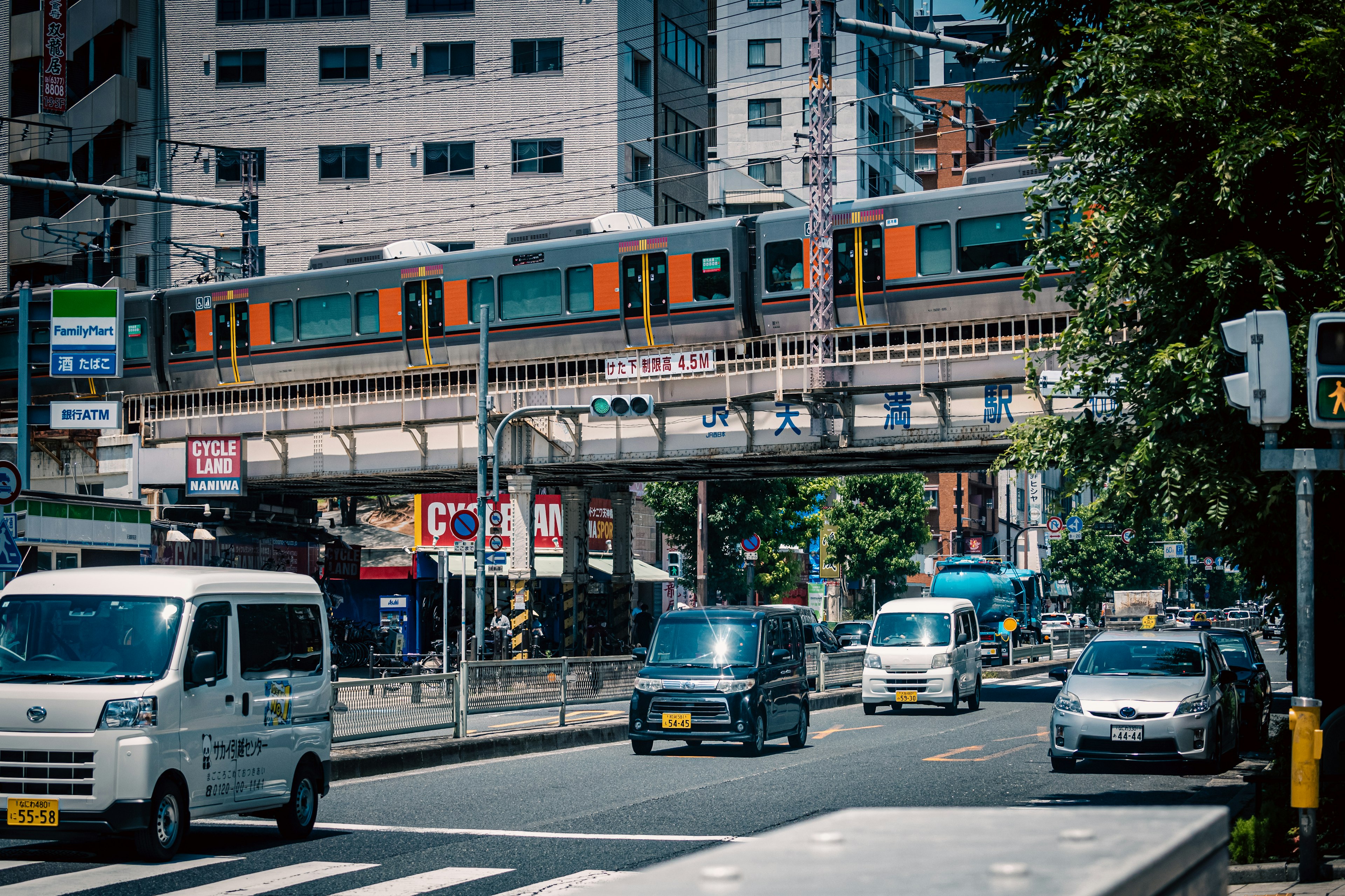 ฉากเมืองที่มีรถไฟยกระดับและรถยนต์บนถนน