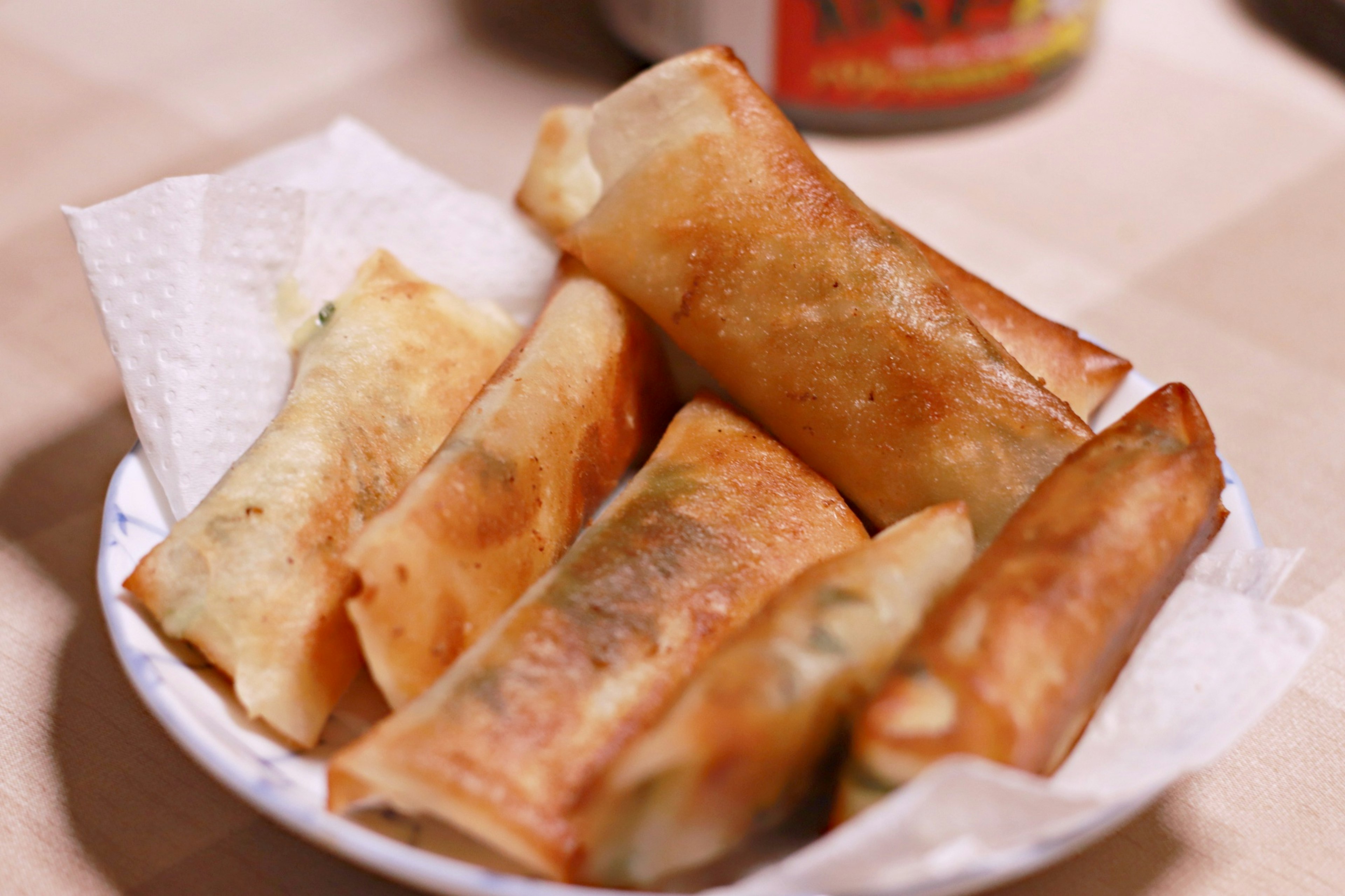 Fried spring rolls arranged on a white plate with a paper towel