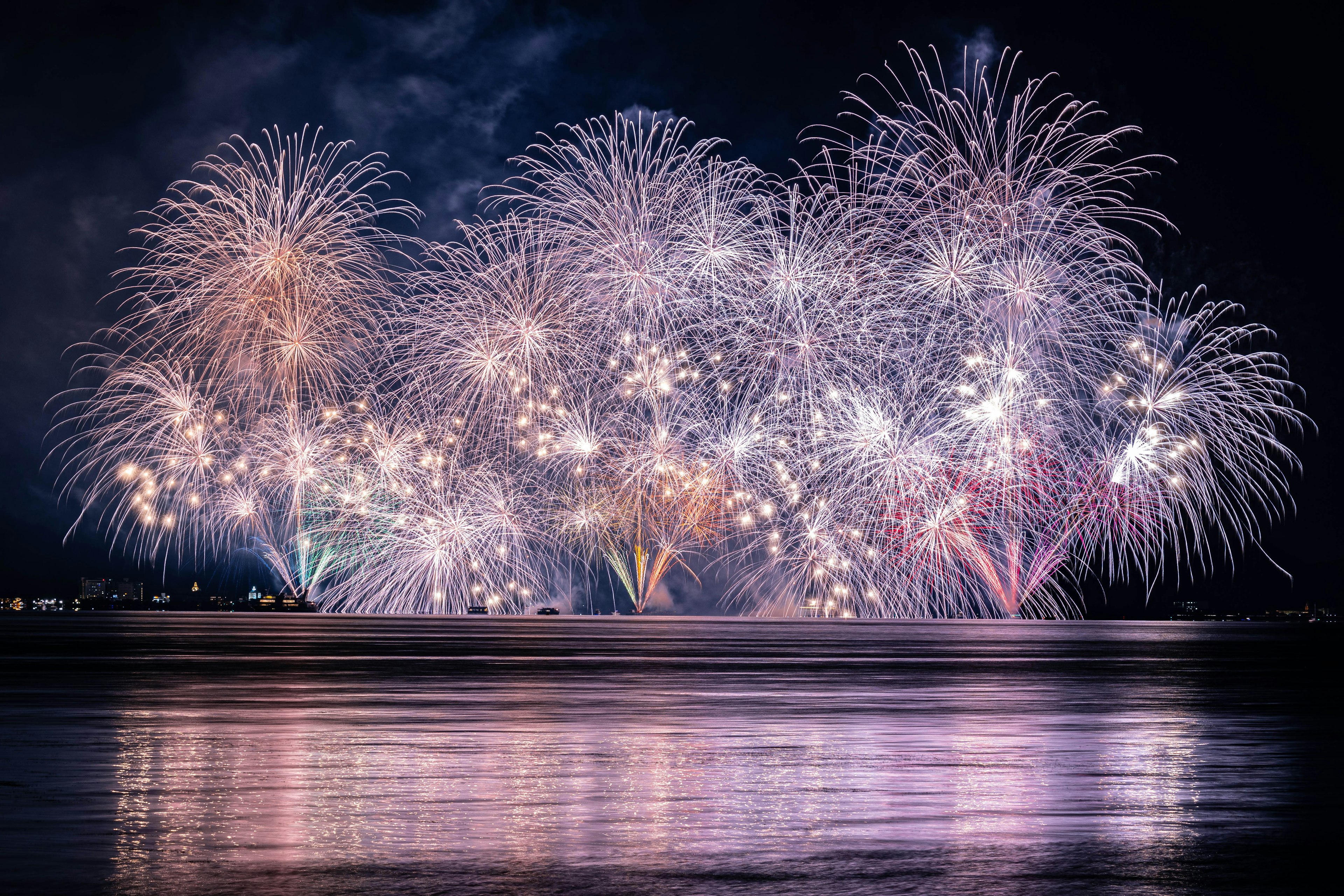 Eine wunderschöne Feuerwerkshow am Nachthimmel mit Reflexionen im Wasser