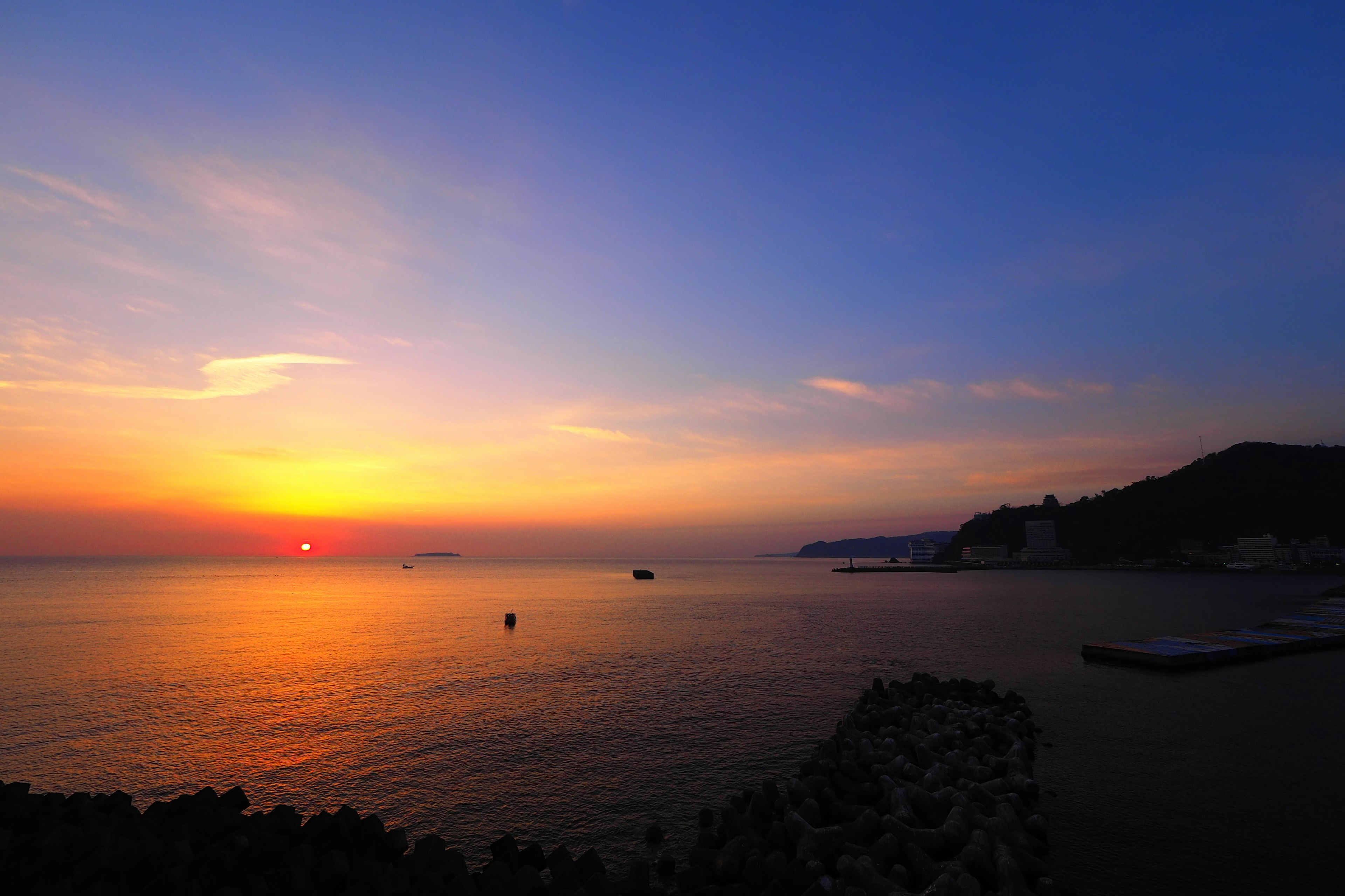 Pemandangan matahari terbenam yang indah di atas laut dengan gradasi biru dan oranye di langit