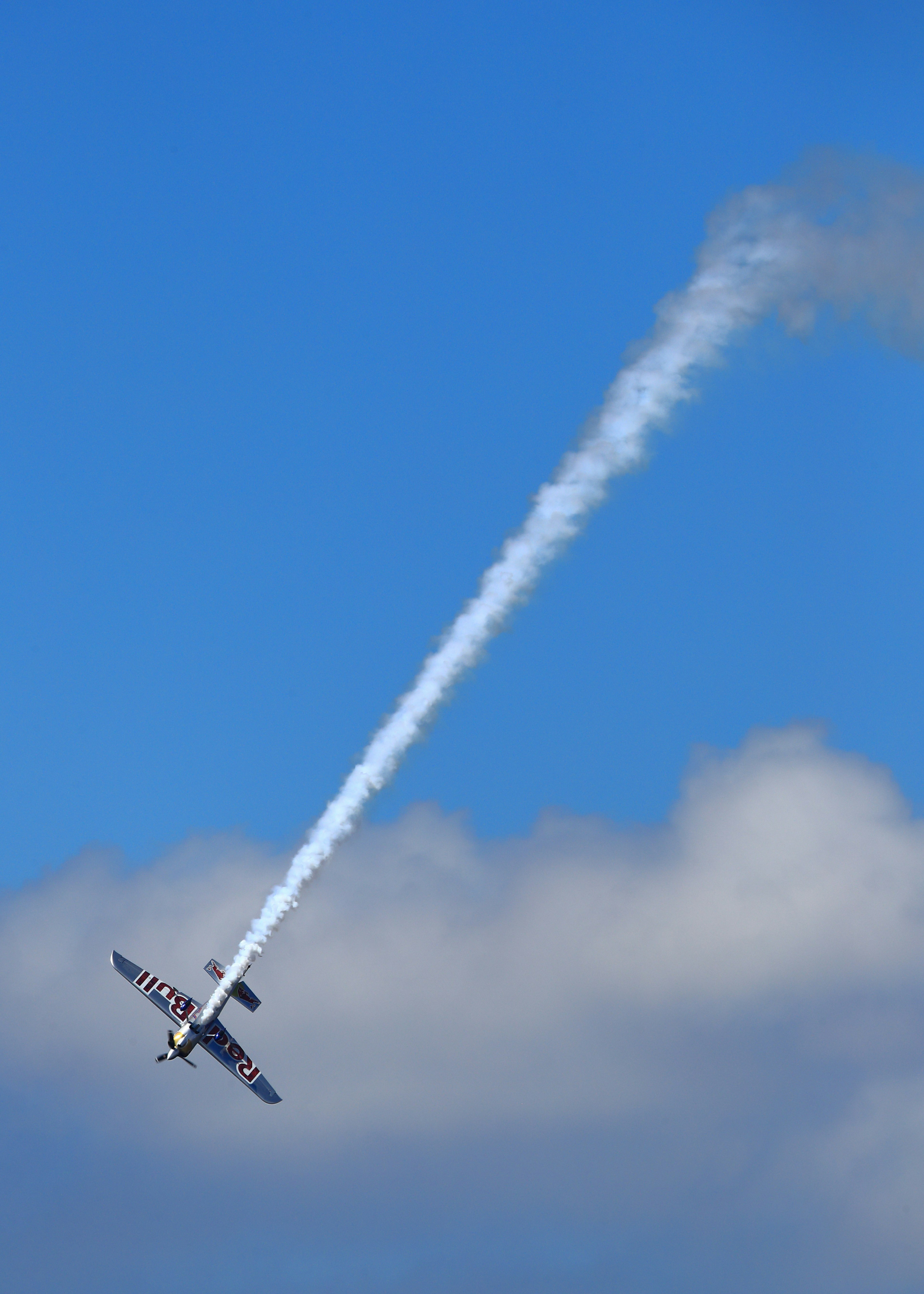 An airplane performing a maneuver while emitting smoke against a blue sky