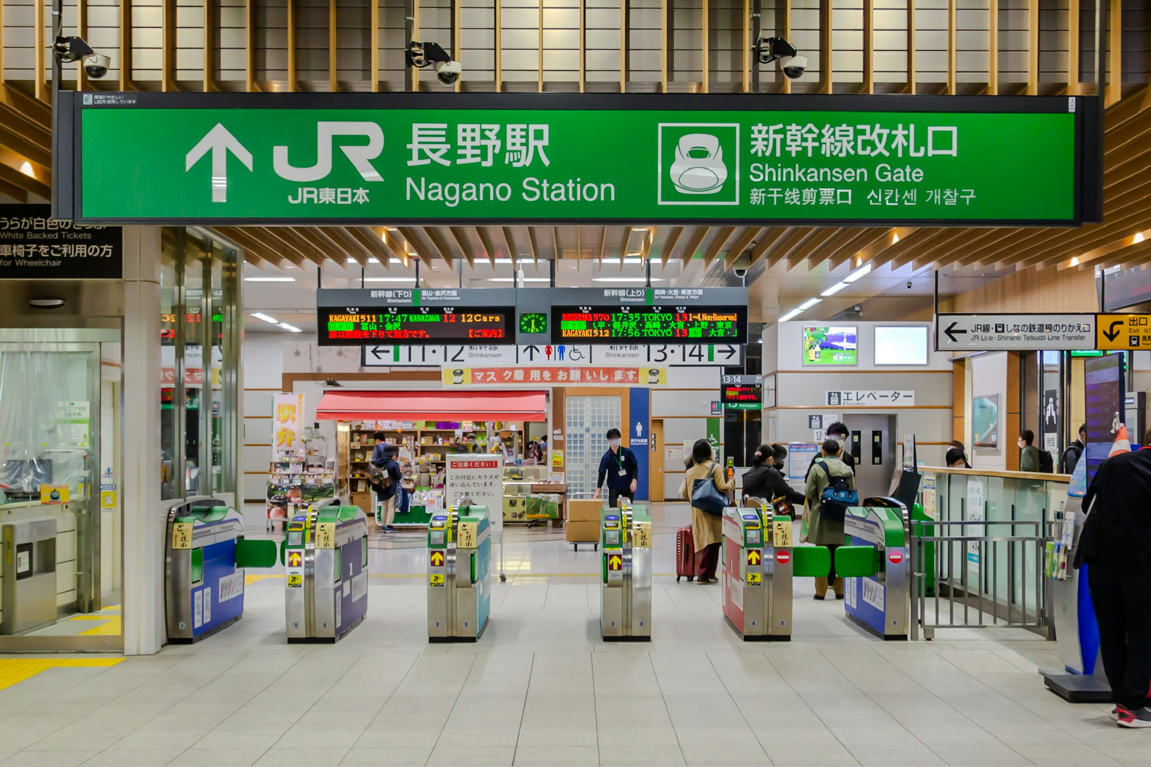 Eingang des Nagano Bahnhofs mit Ticketautomaten und grüner Beschilderung