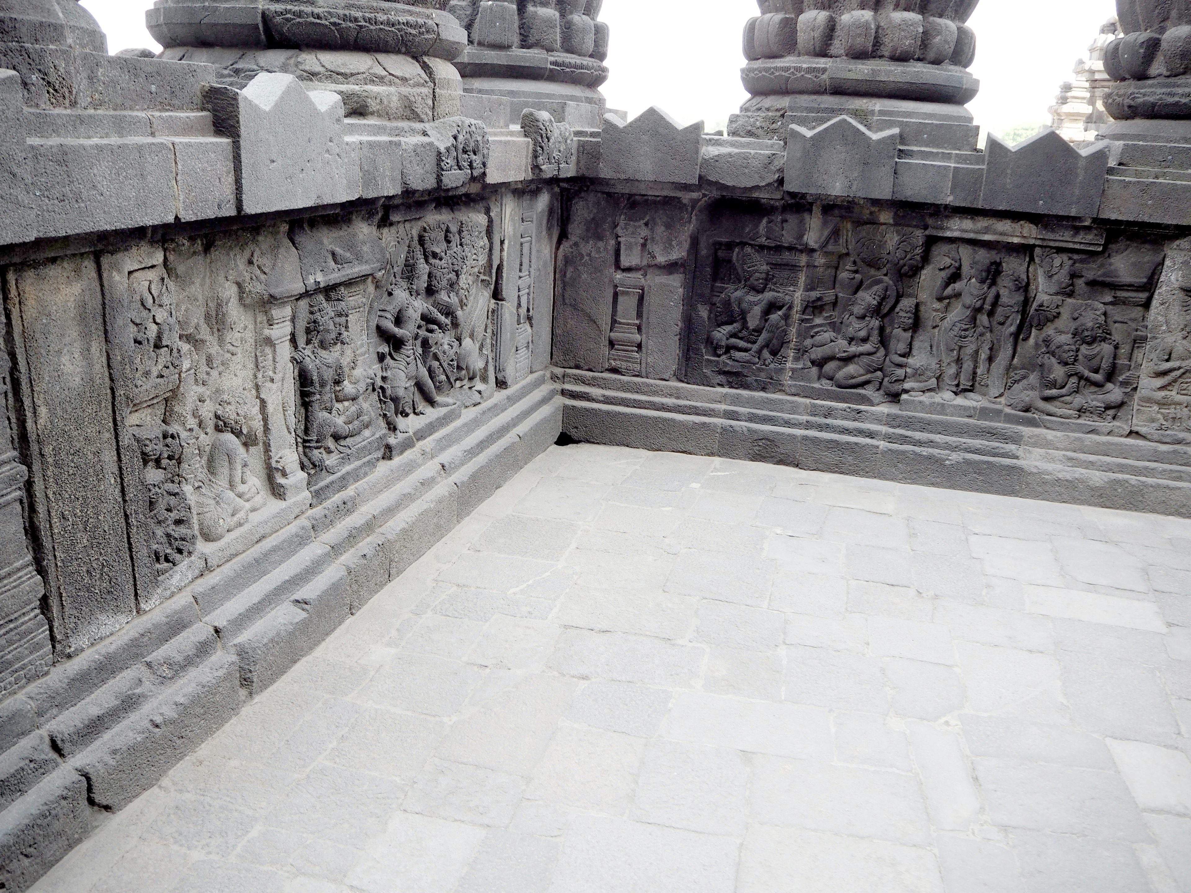 Esquina de un antiguo templo con tallas de piedra en la pared y un suelo de piedra