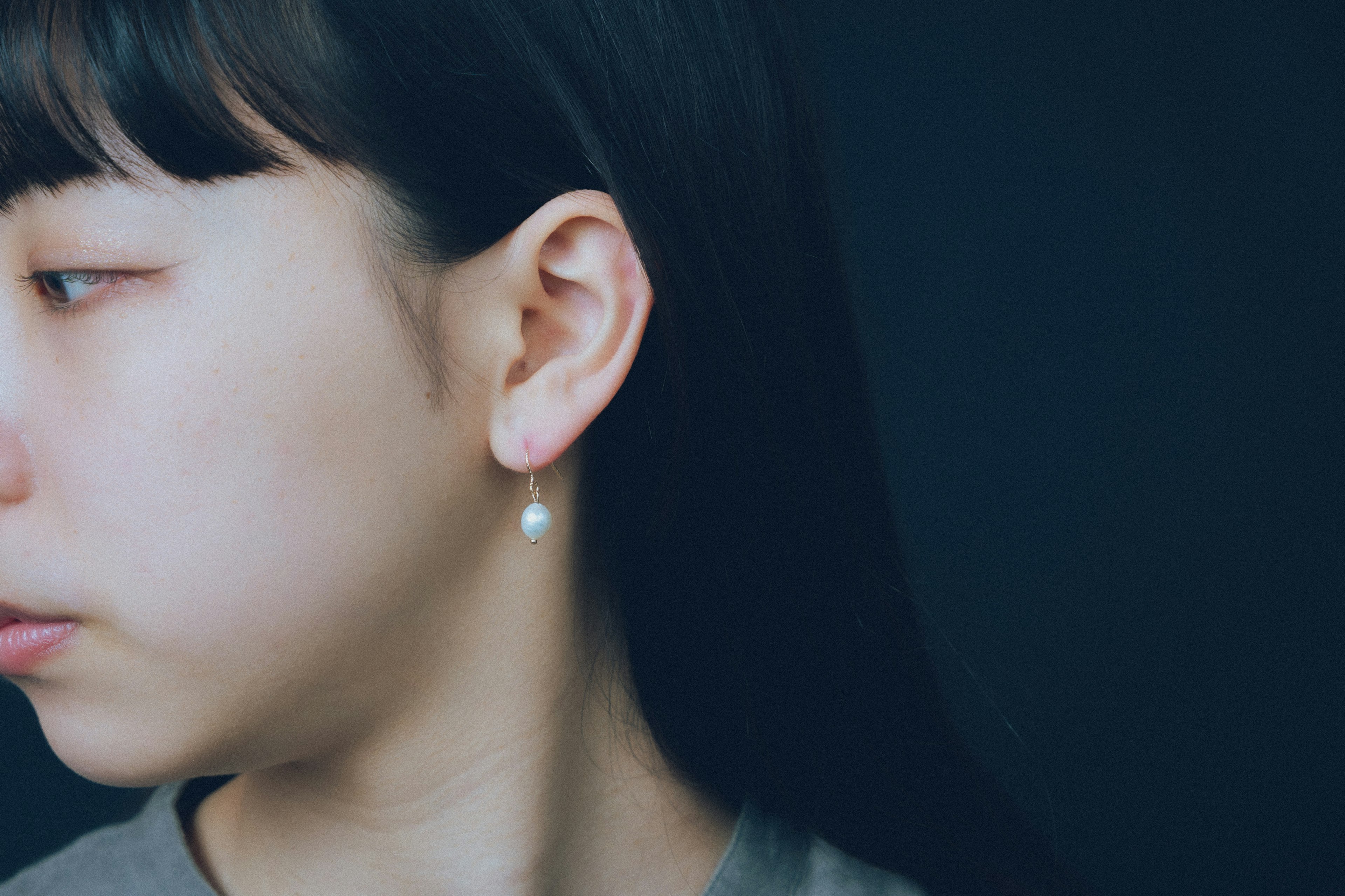 Profil d'une femme avec une boucle d'oreille en perle sur fond sombre