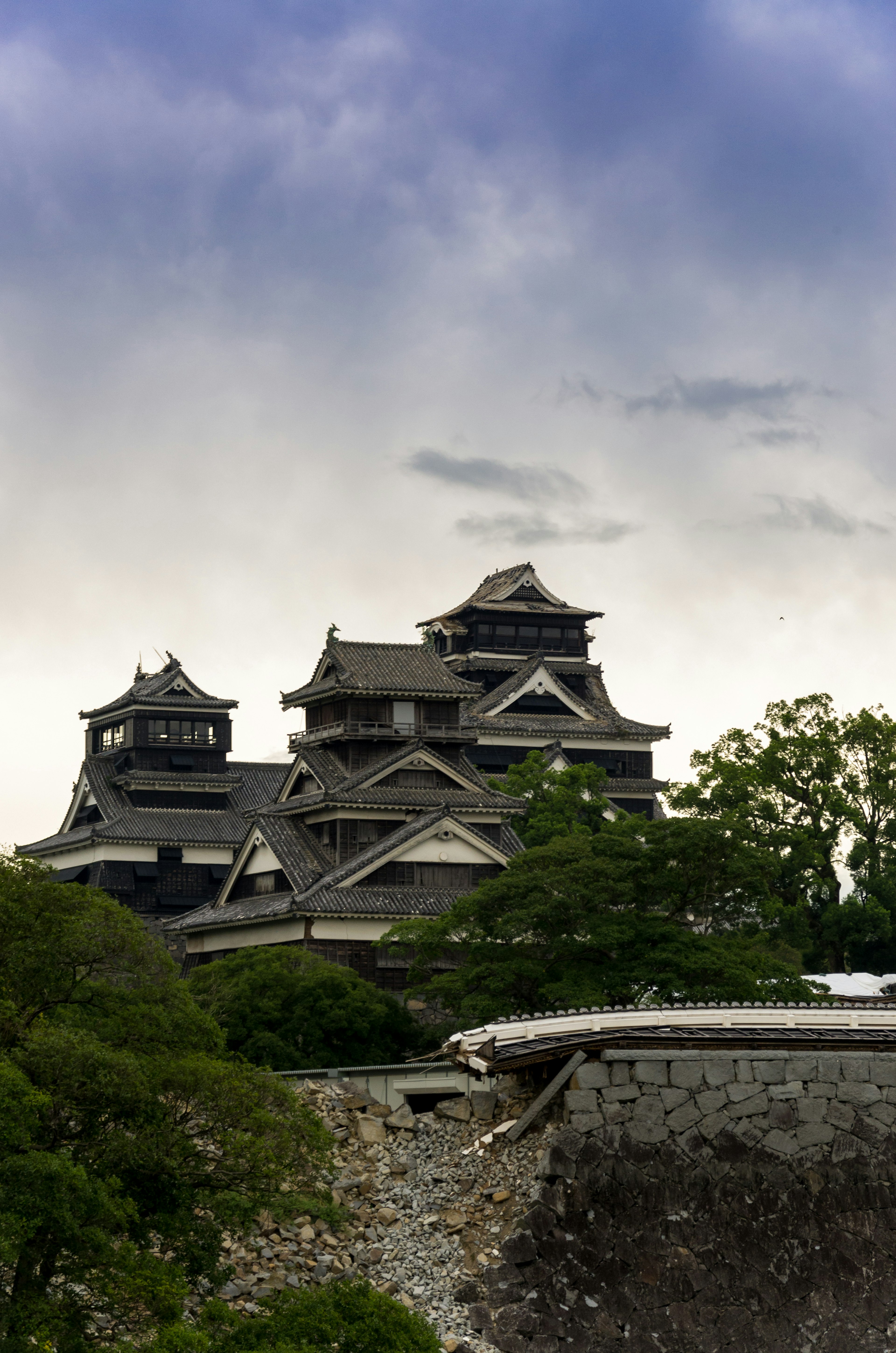 Die schöne Fassade von Kumamoto Castle mit grünen Bäumen