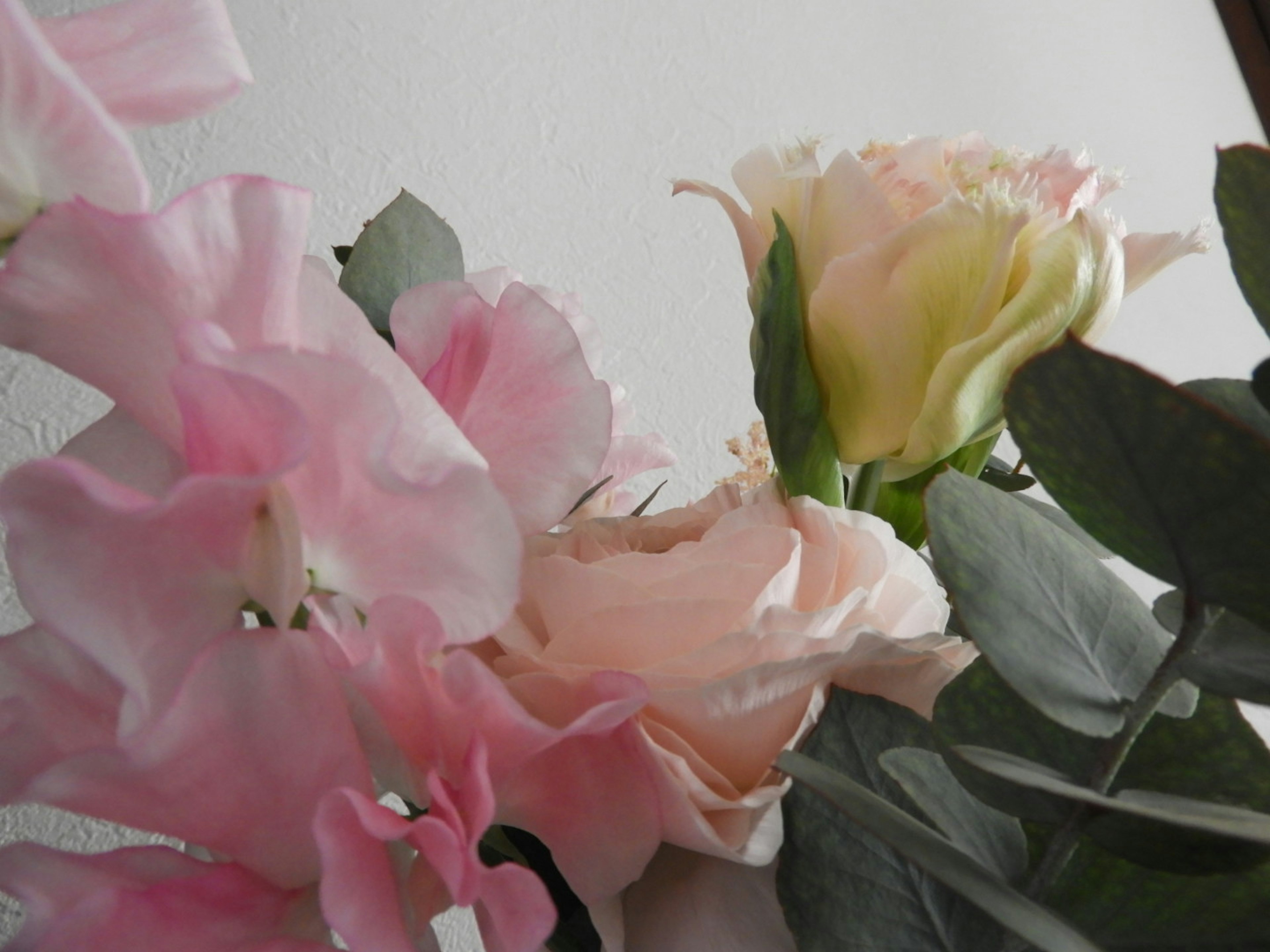 Arrangement of pale pink and cream flowers with green leaves