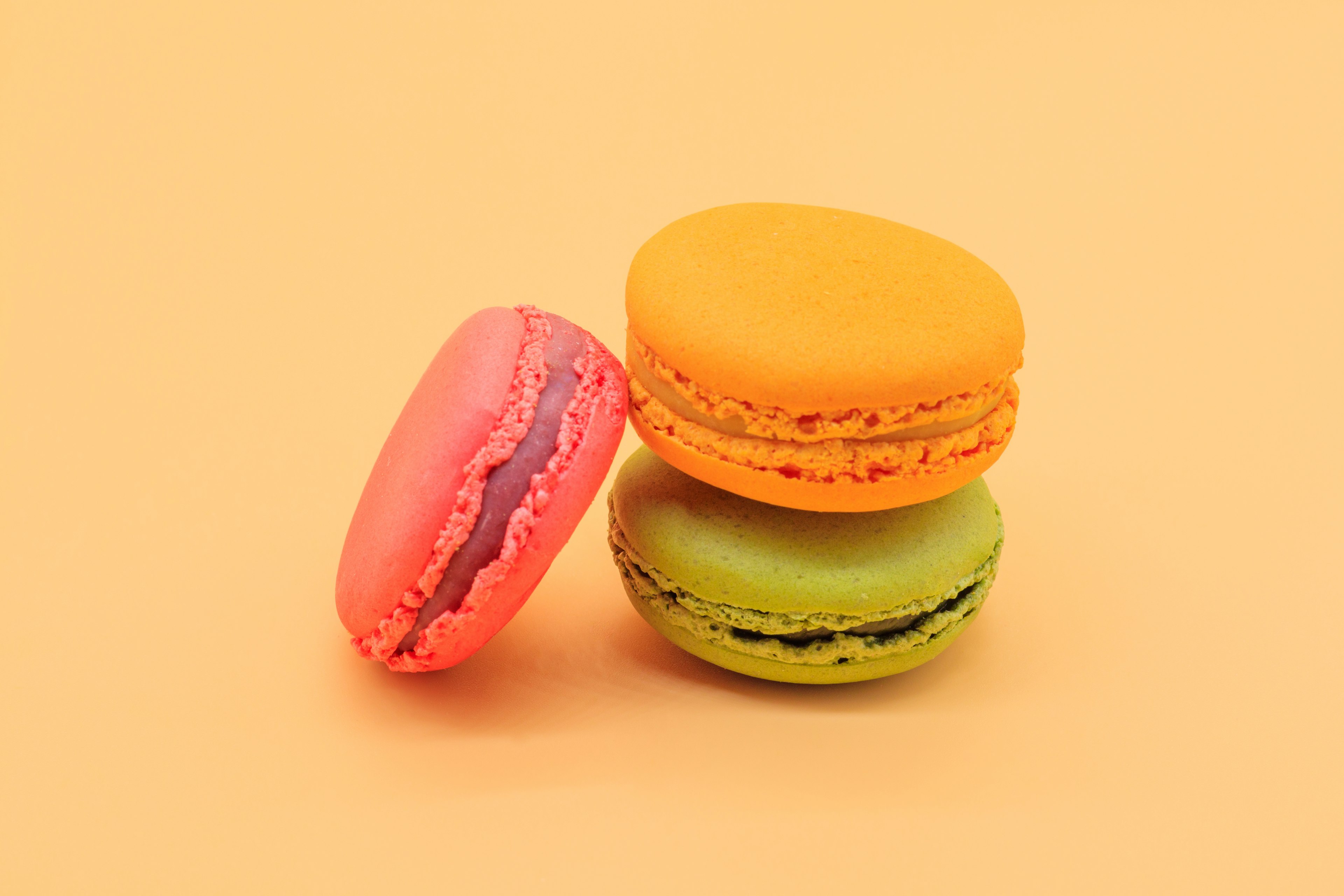 Tres macarons coloridos apilados sobre un fondo amarillo