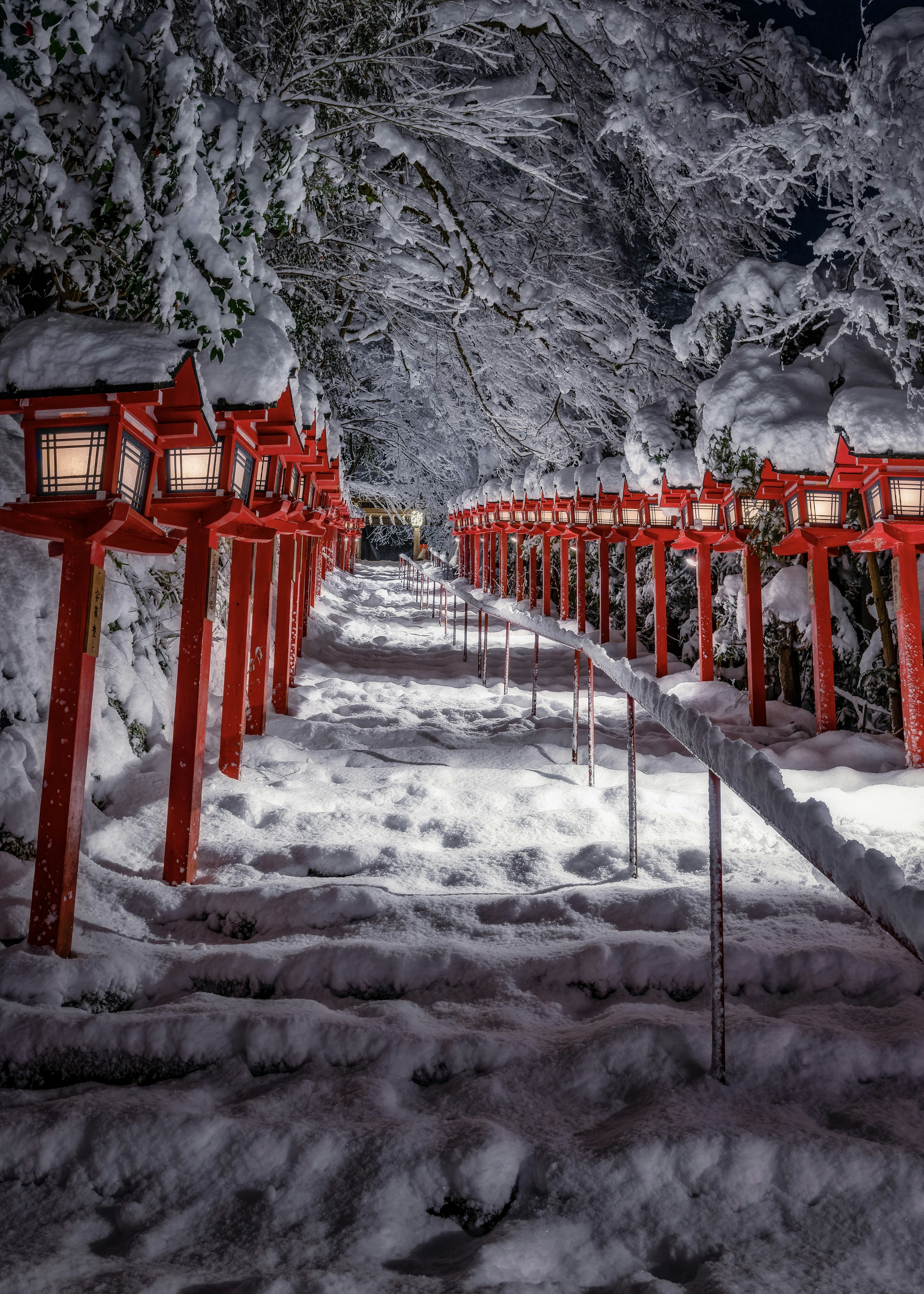 Sentiero coperto di neve fiancheggiato da lanterne rosse