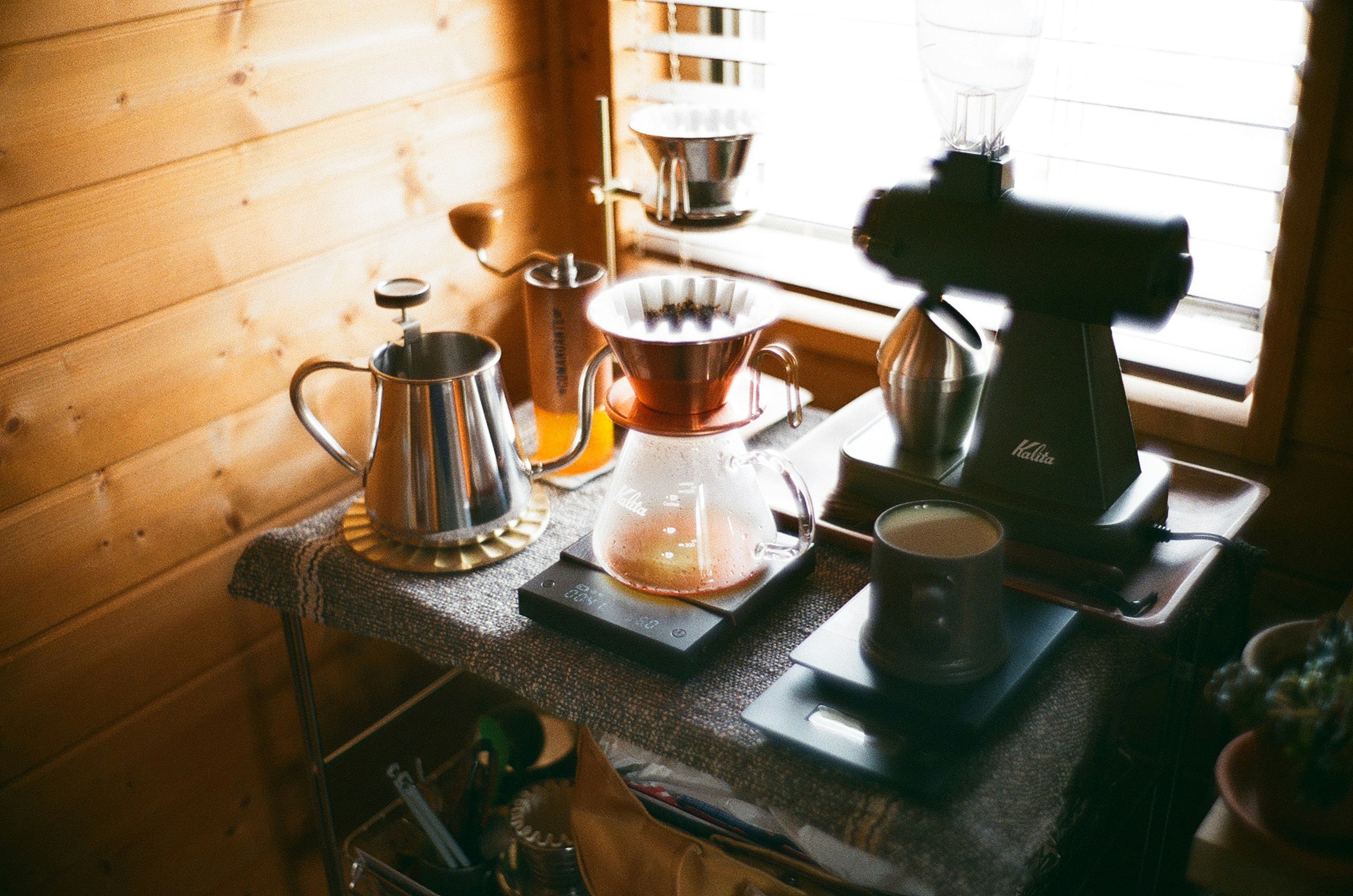 Coffee brewing equipment arranged on a wooden table in a cozy room