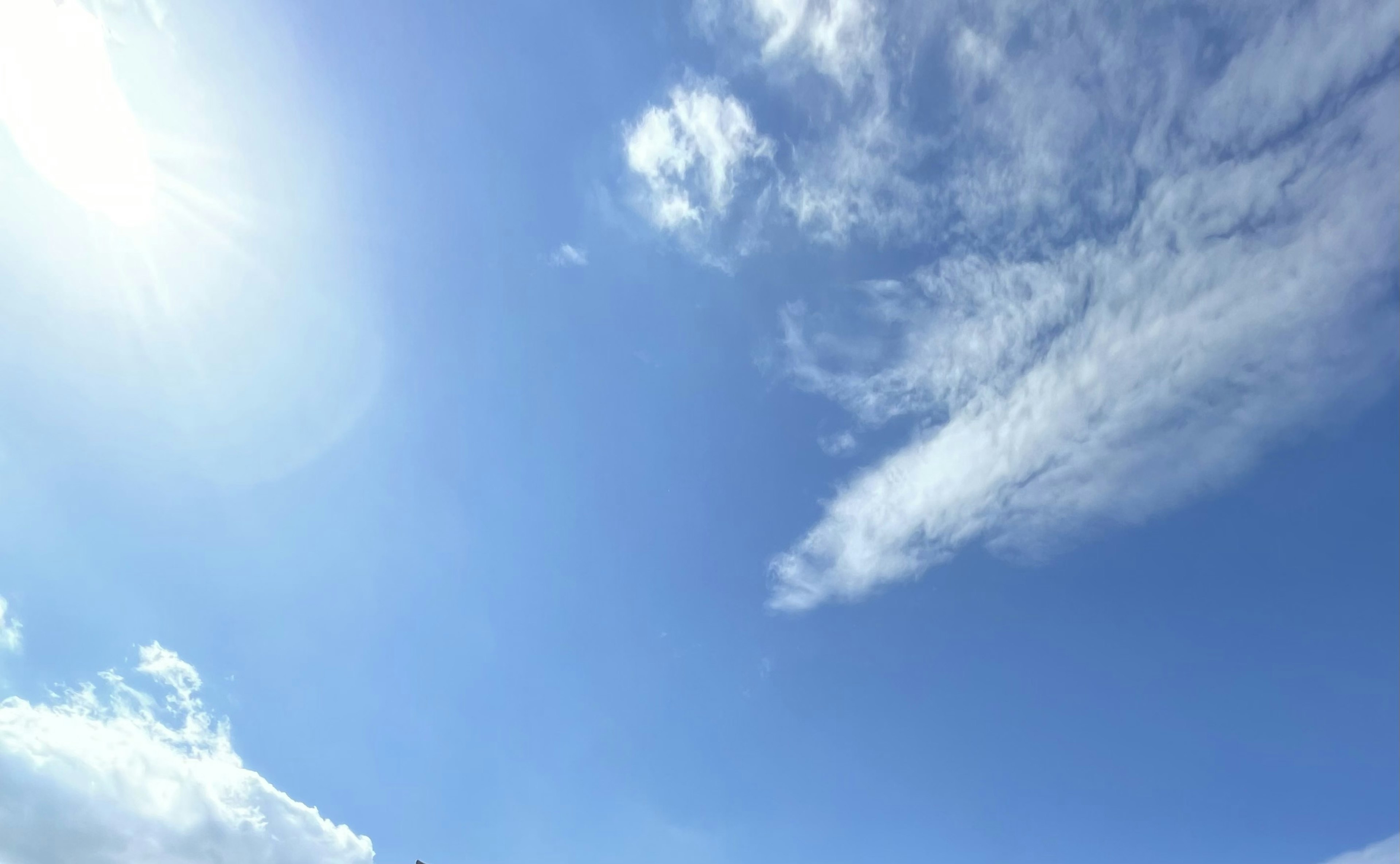 A clear blue sky with wispy white clouds