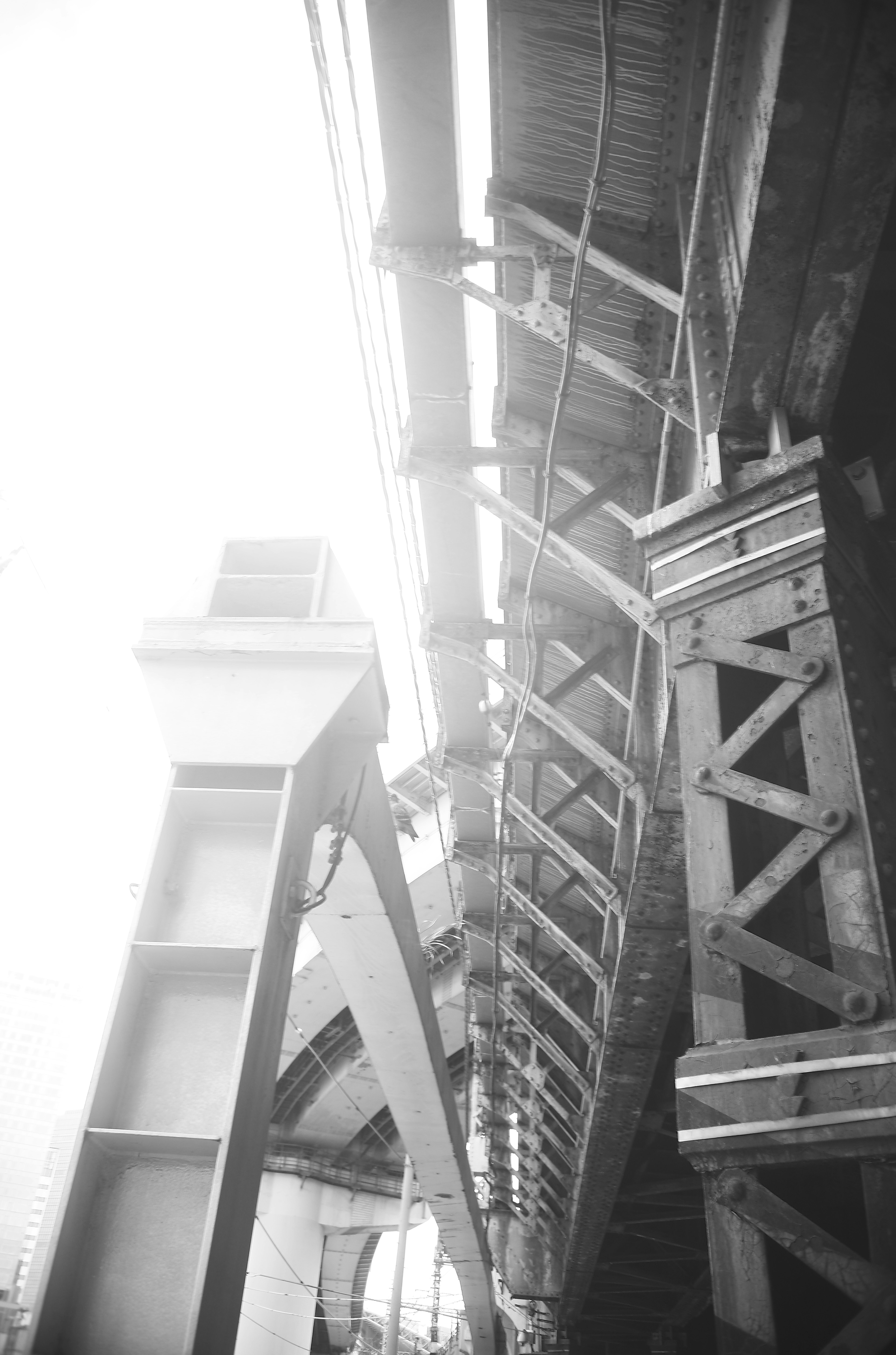 Schwarzweißfoto einer Brücke von unten mit strukturellen Elementen