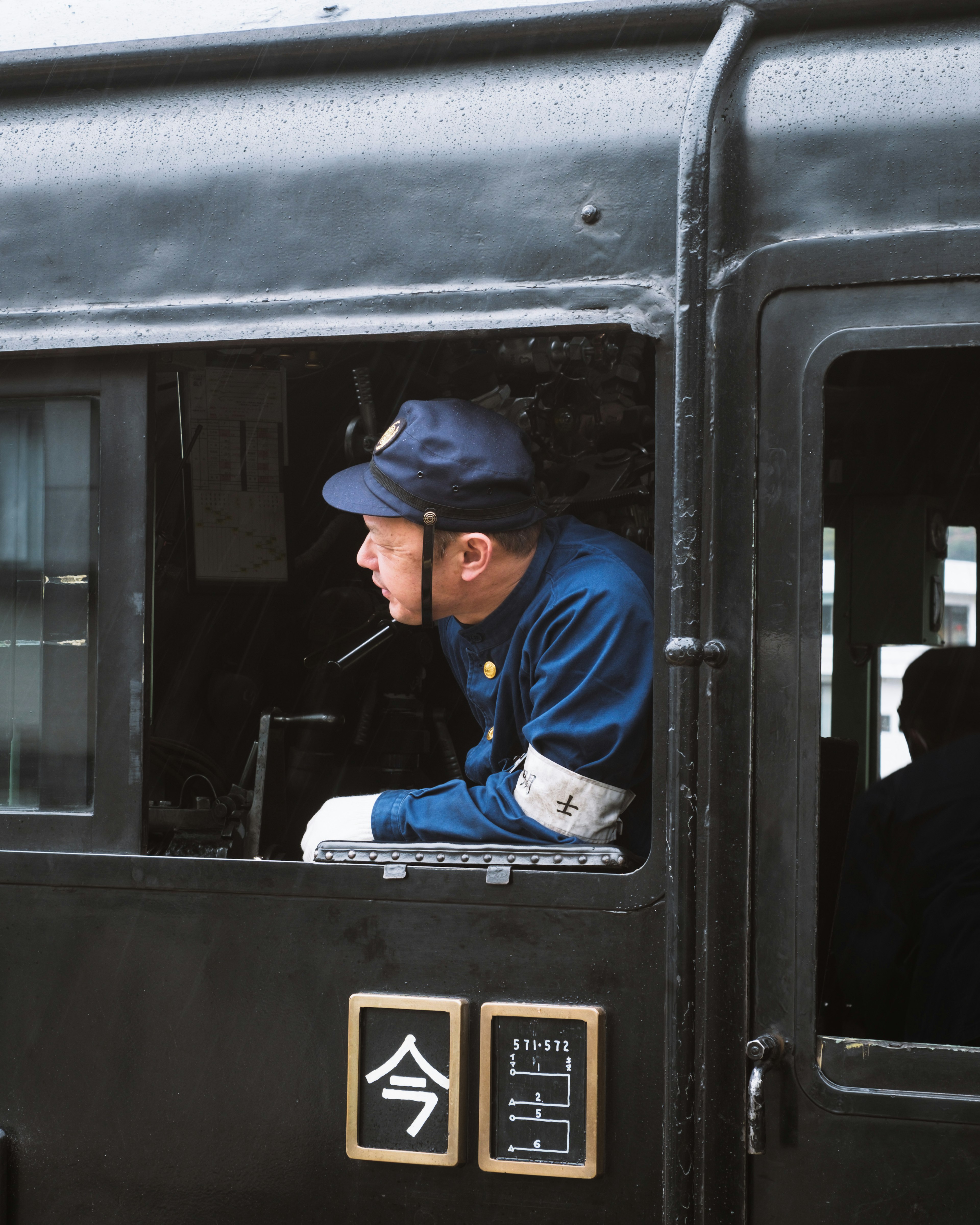 Train conductor looking out from the window of a black locomotive cab