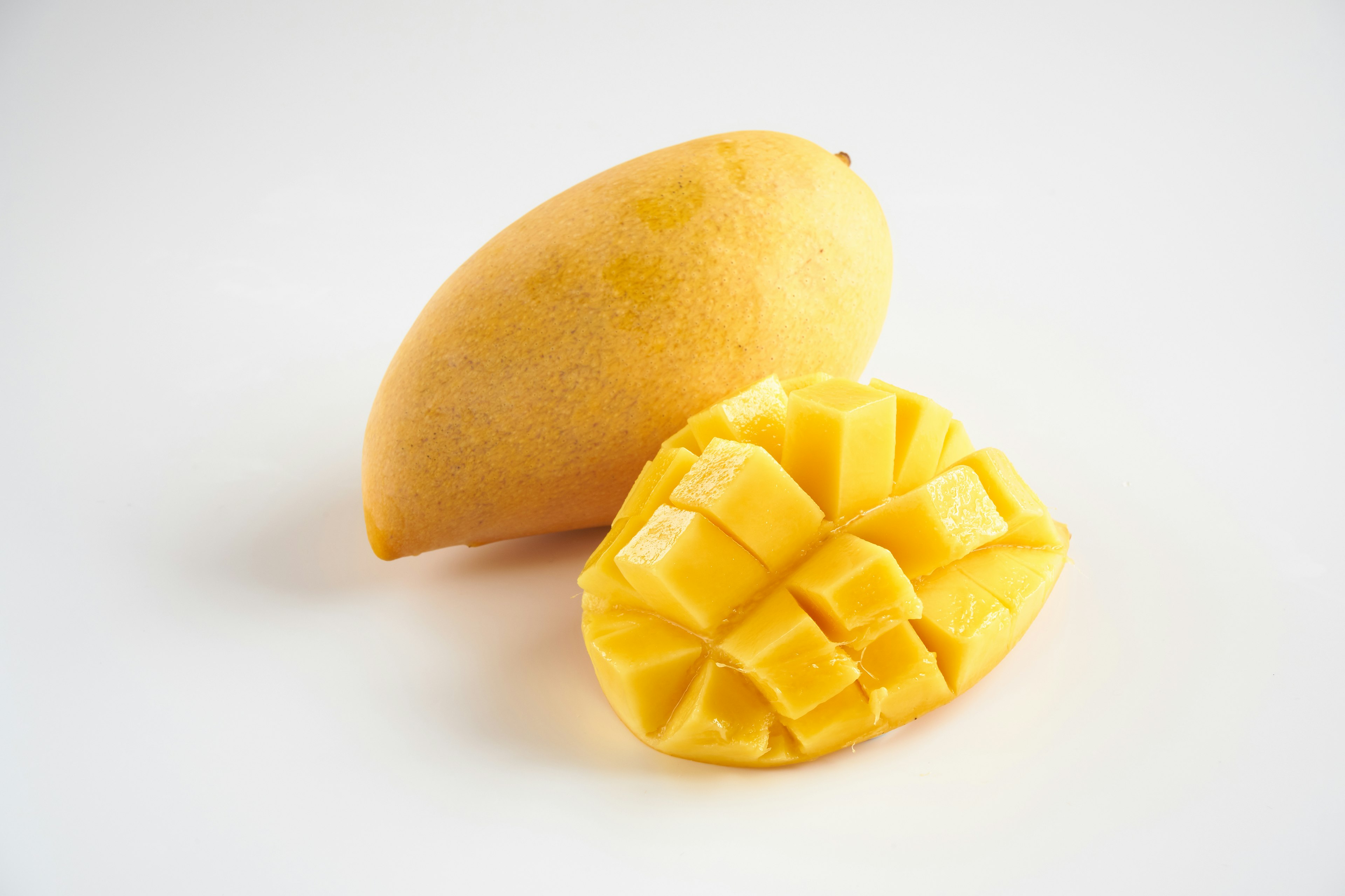 A whole mango and a sliced mango half on a white background