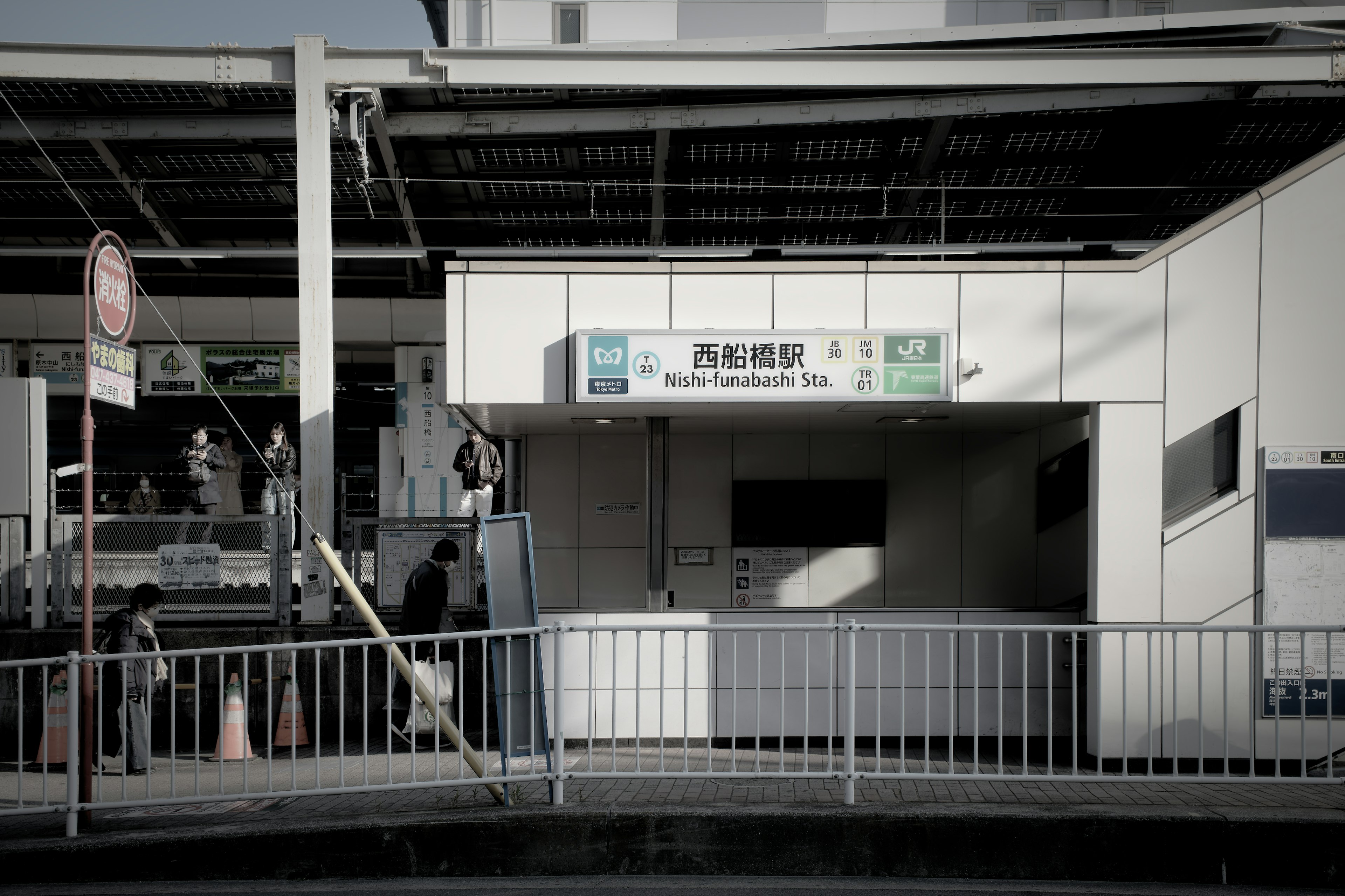 Entrance of a train station with people passing by