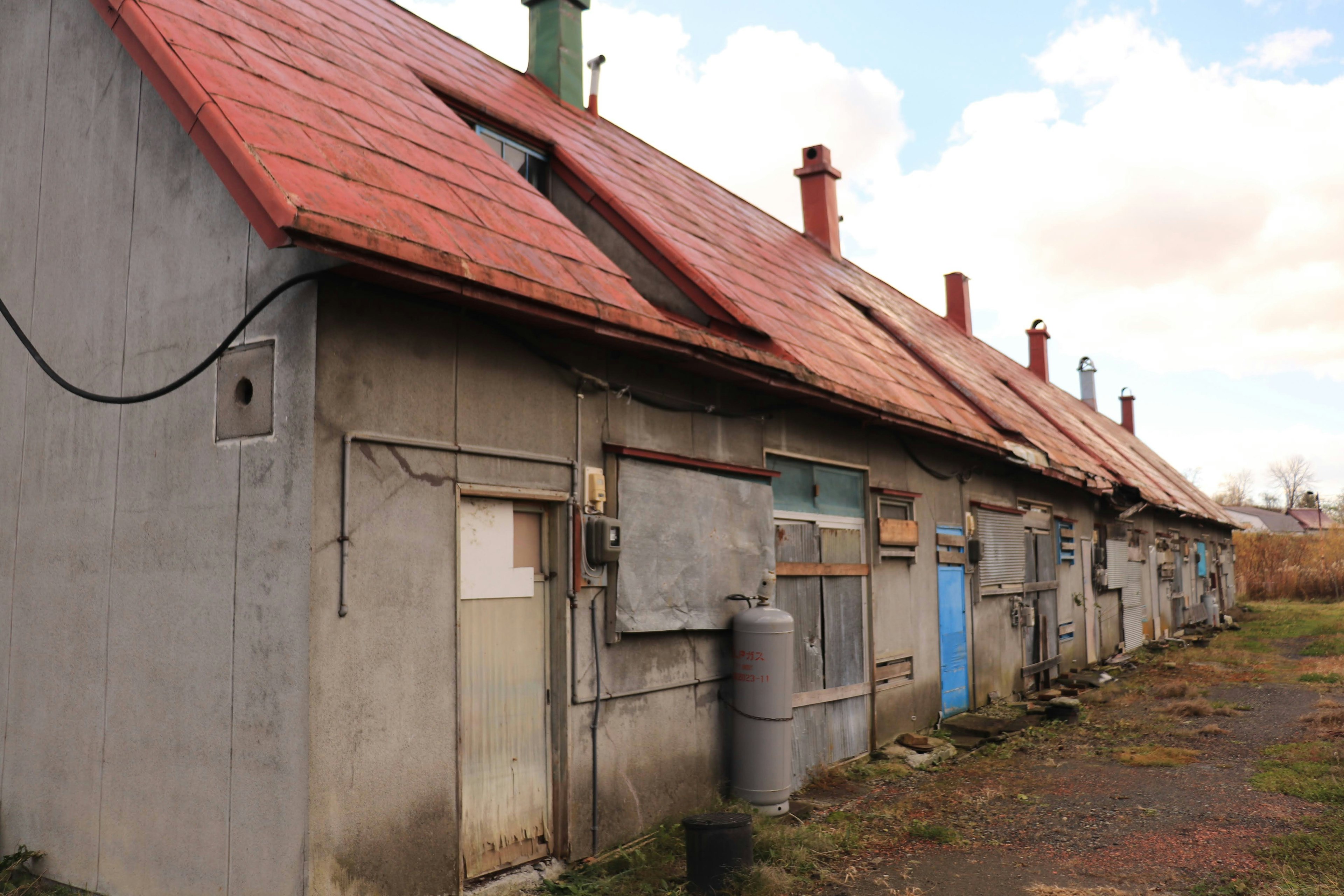 Row of old buildings with red roofs featuring several windows and doors