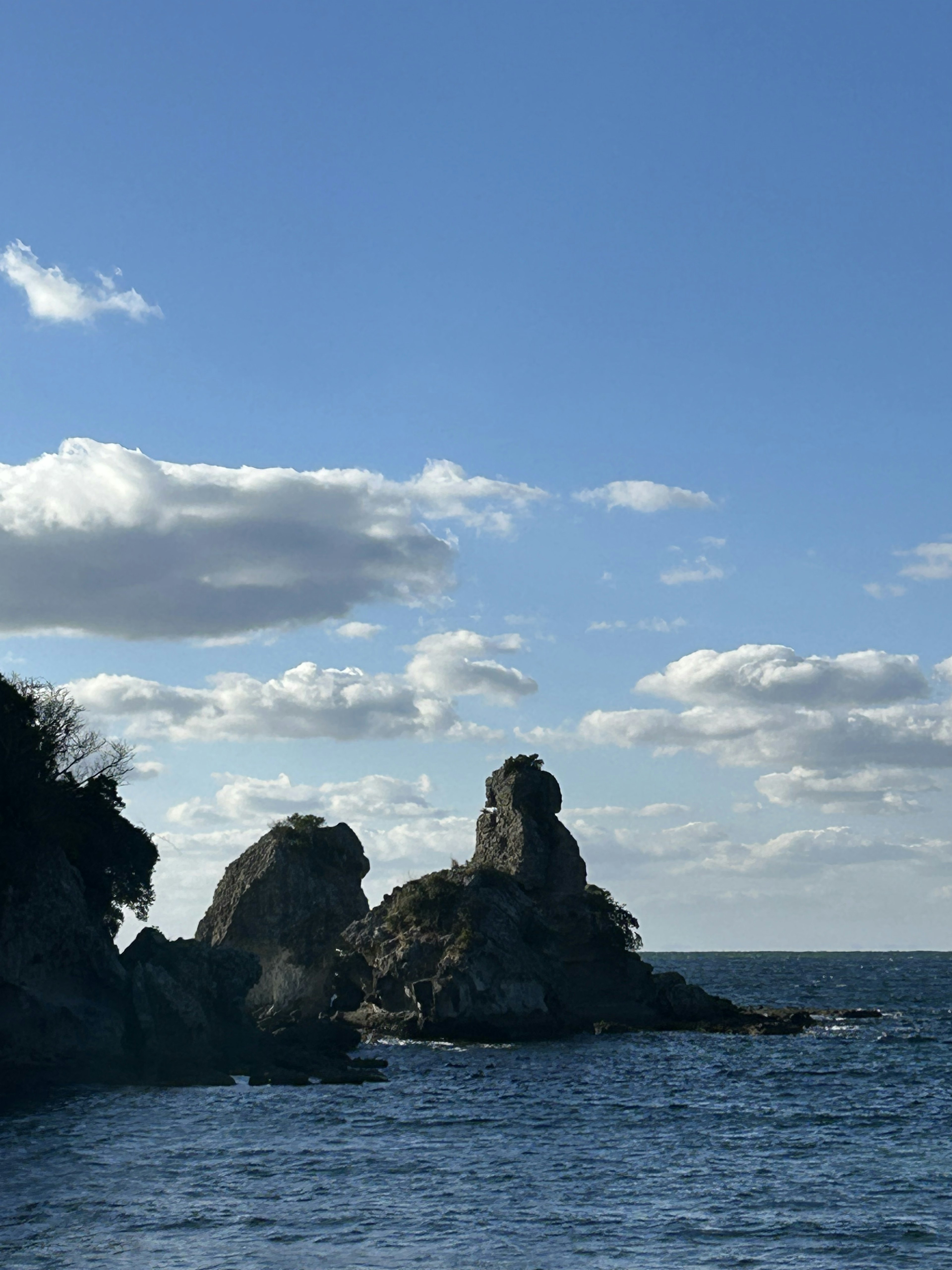 青い海と雲の下にある岩礁の景観