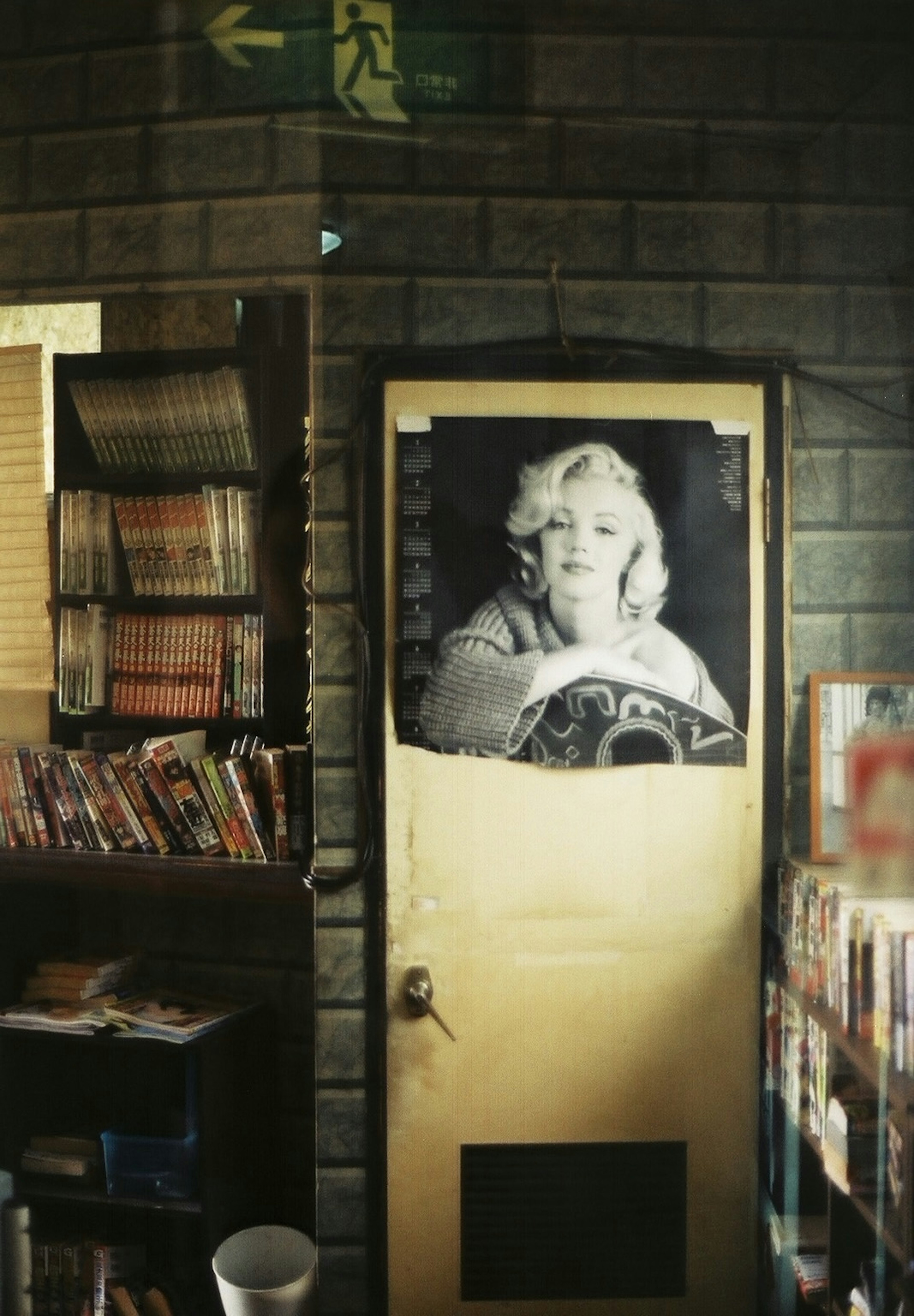 Interior perpustakaan tua dengan pintu kuning dan poster hitam putih Marilyn Monroe