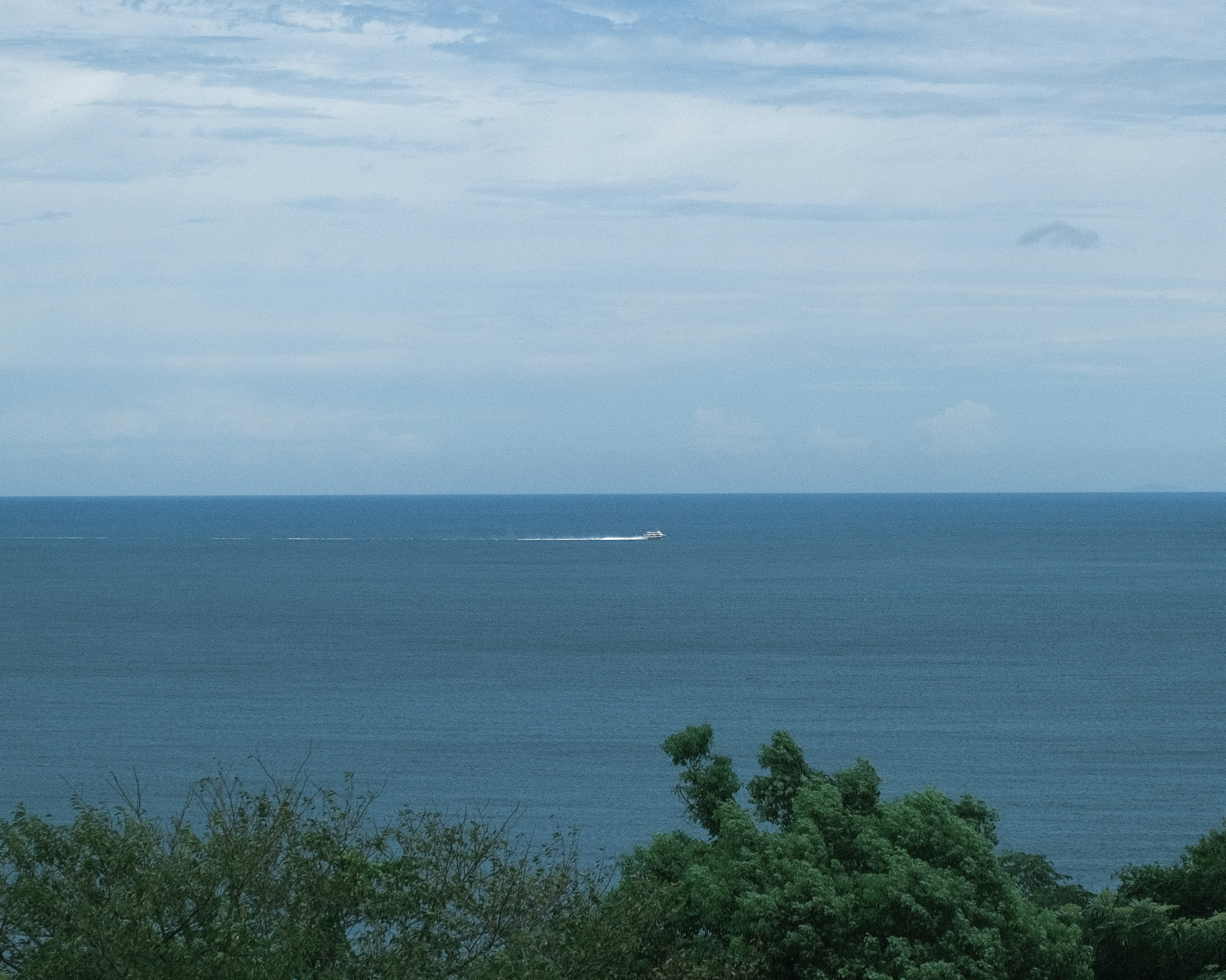 青い海と空の風景に小さな船が浮かんでいる