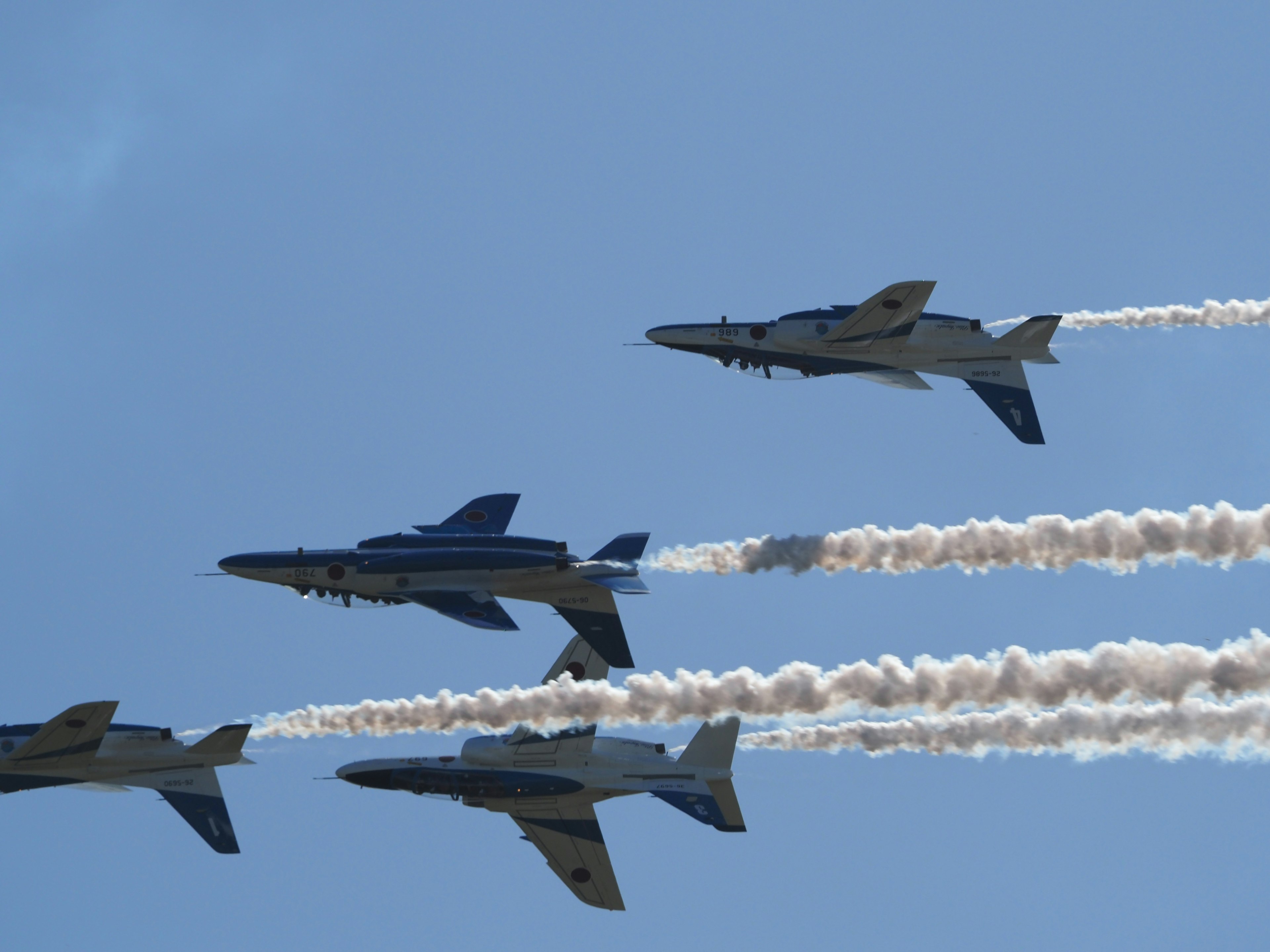 Formation flying of military jets in blue sky leaving smoke trails