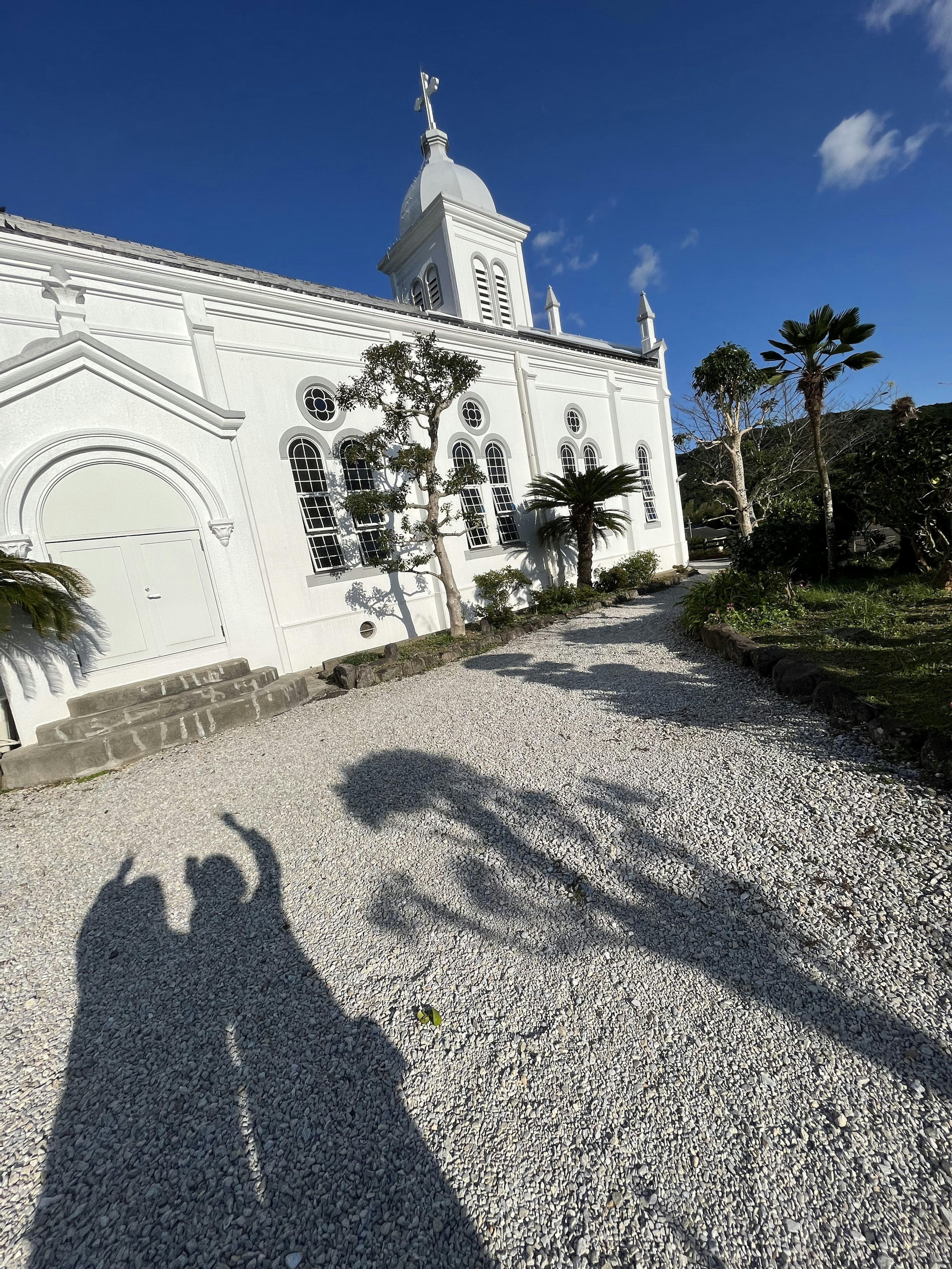 Chiesa bianca con ombre e un sentiero di ghiaia