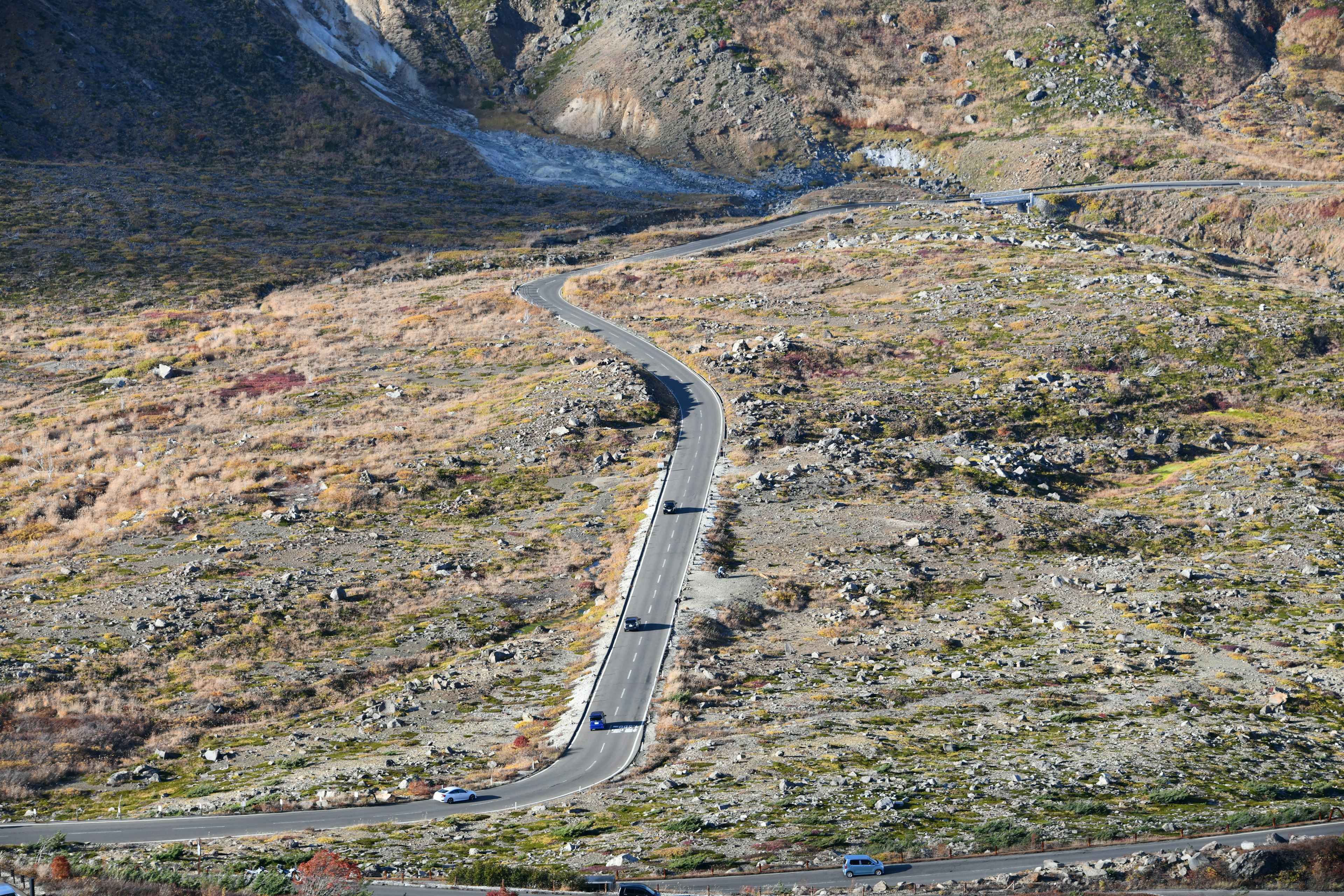 Route sinueuse à travers un paysage sec avec un terrain rocheux