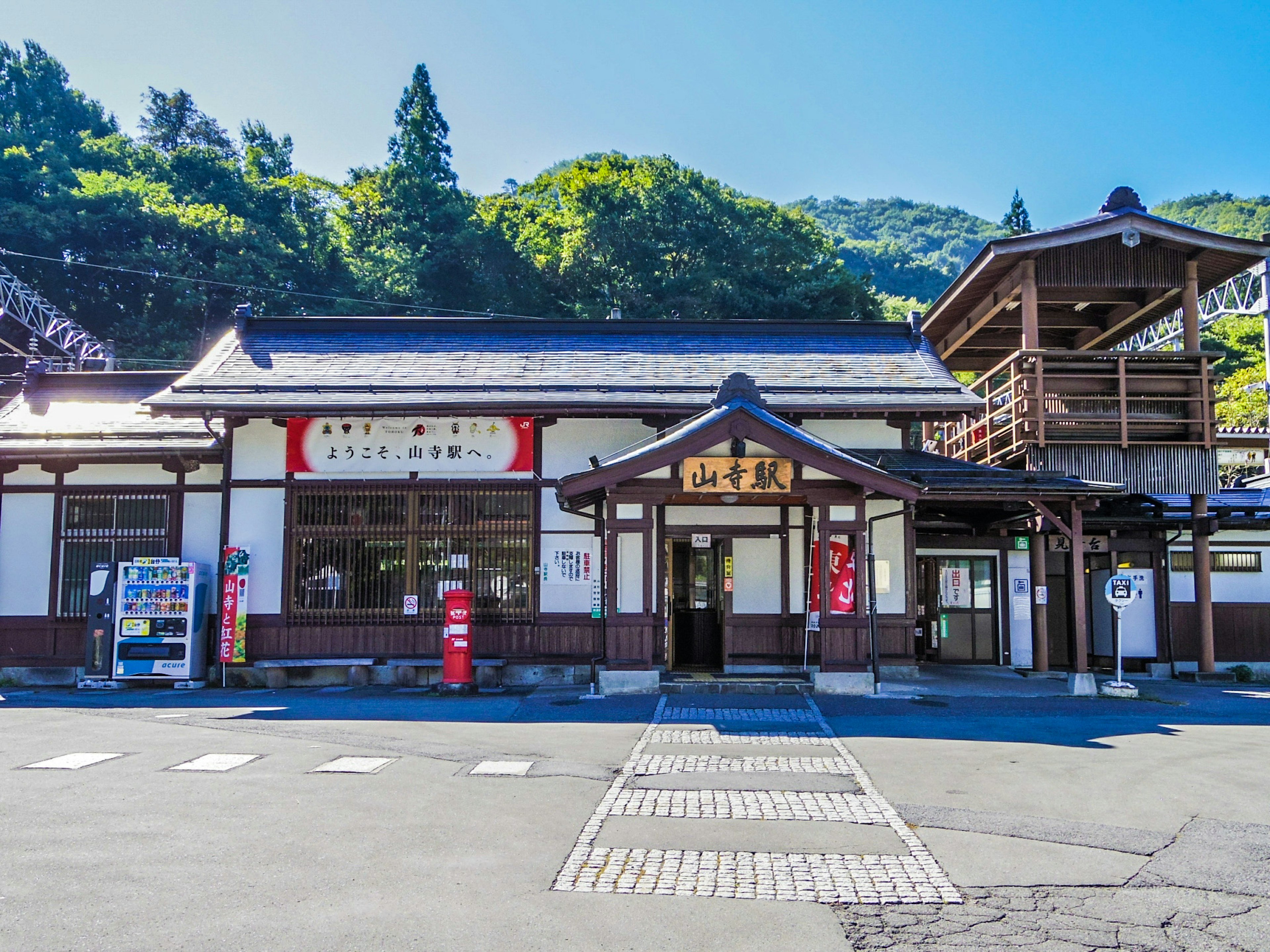 Traditional Japanese train station building surrounded by lush green mountains