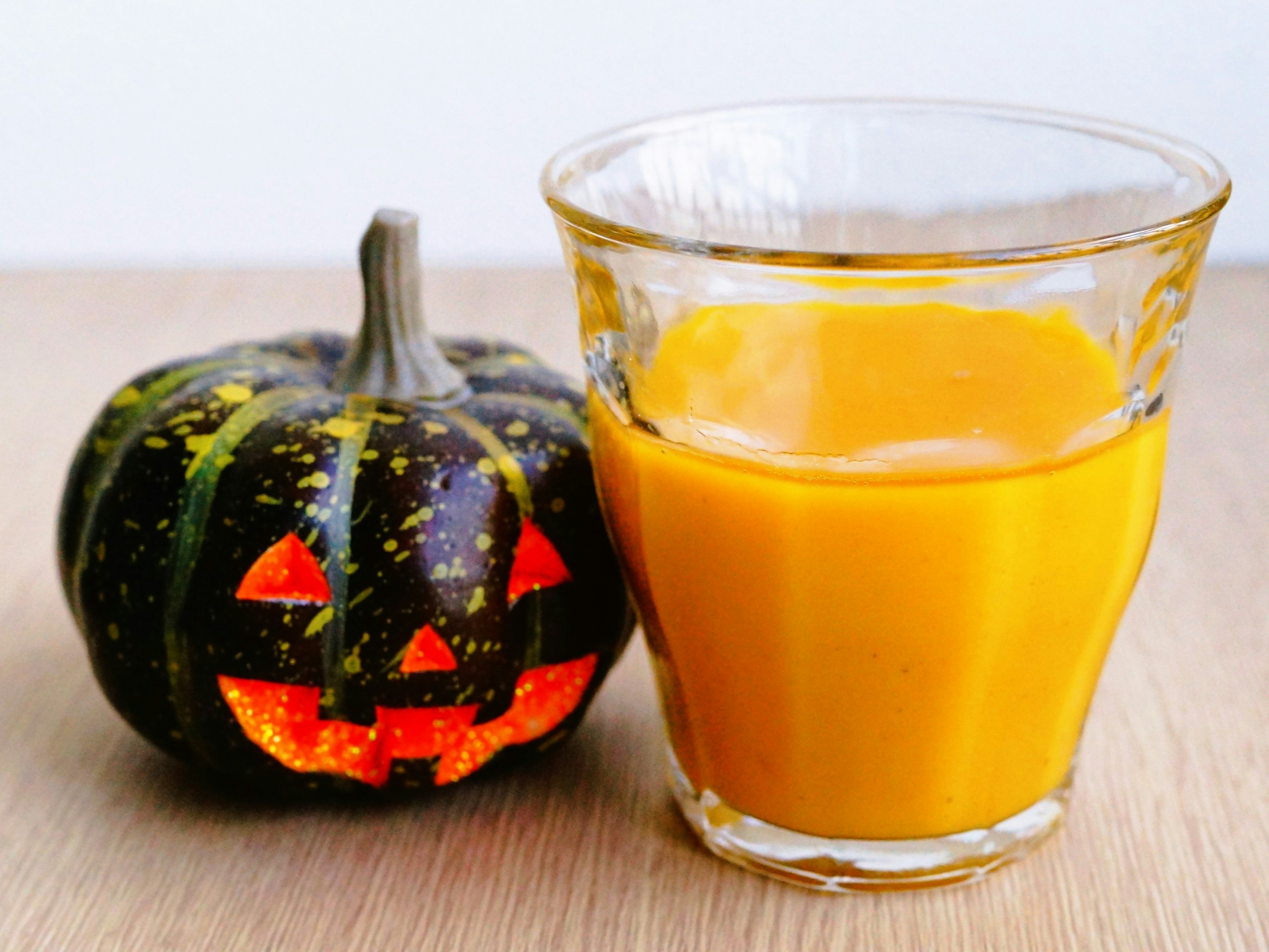 Halloween-Kürbis mit geschnitztem Gesicht und einem Glas Orangensaft