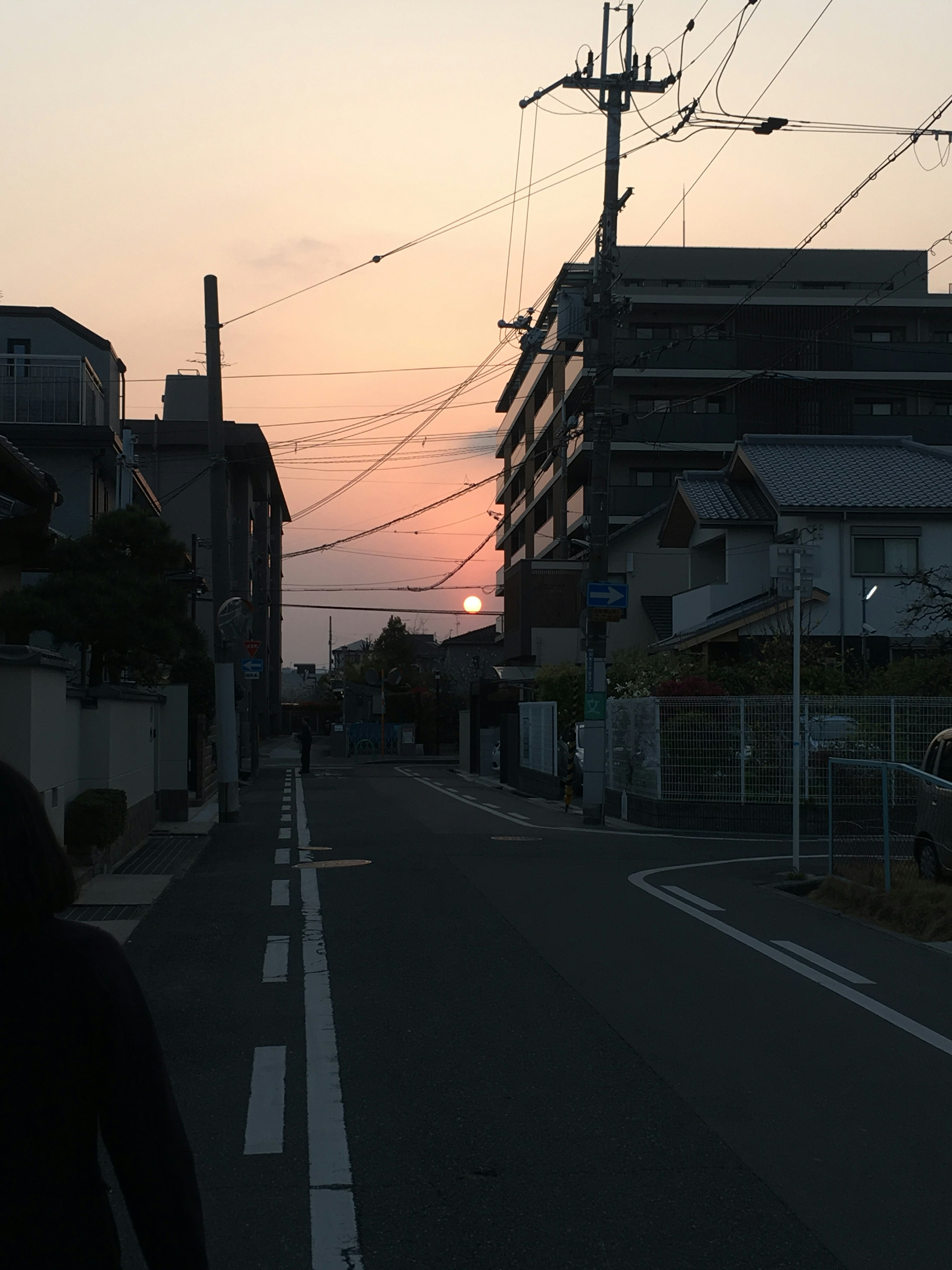 Vista di una strada al tramonto con edifici e linee elettriche