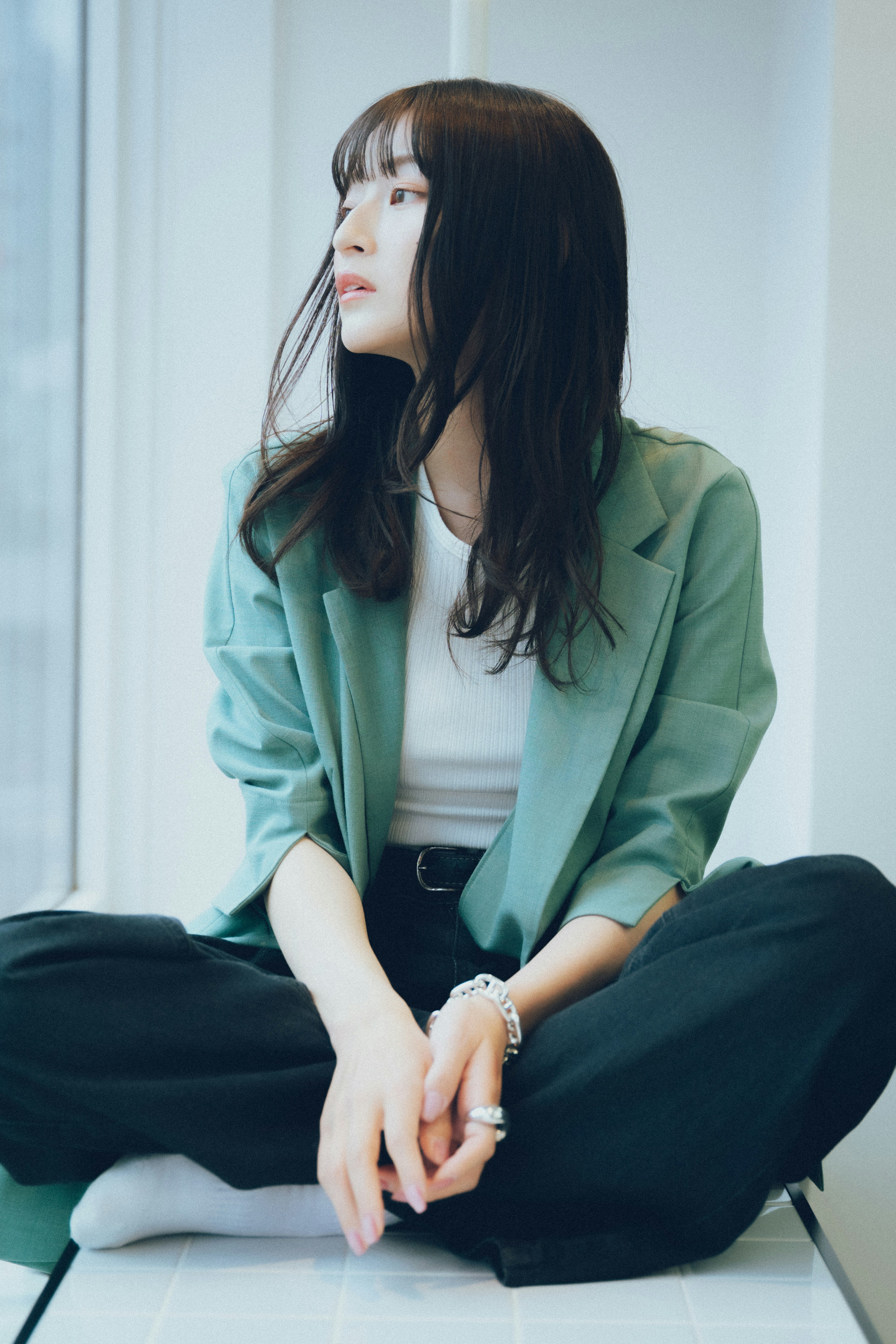 A woman wearing a green blazer sitting by the window