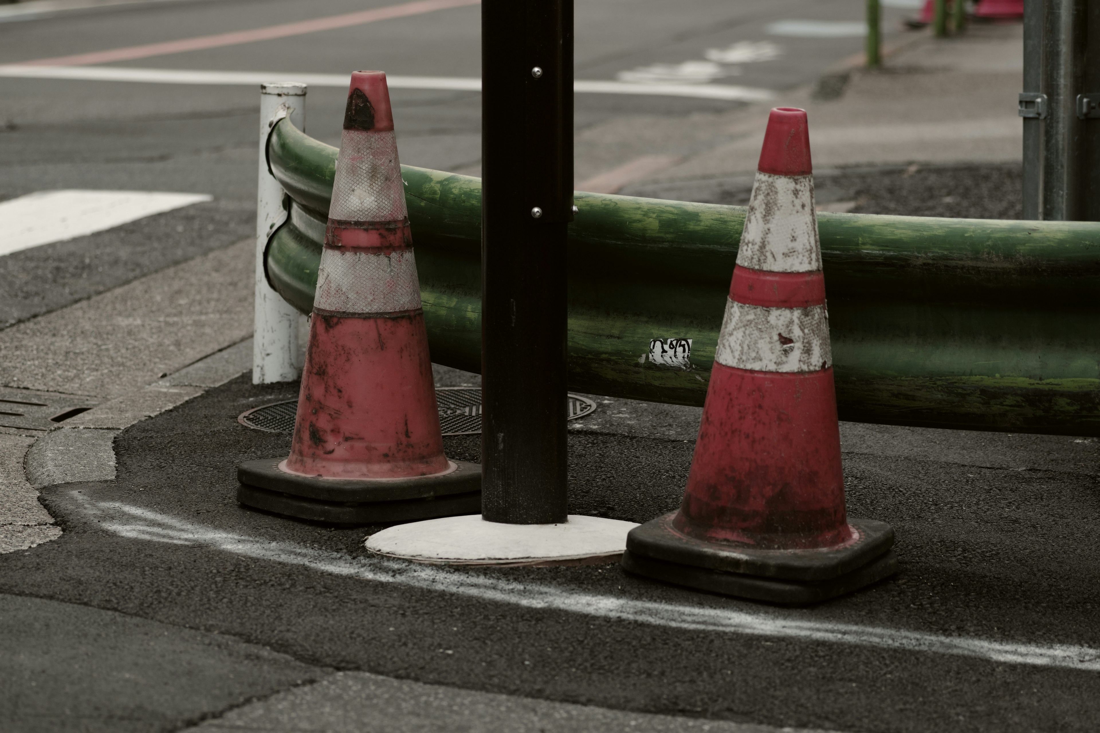 Traffic cones and green barrier at a street corner