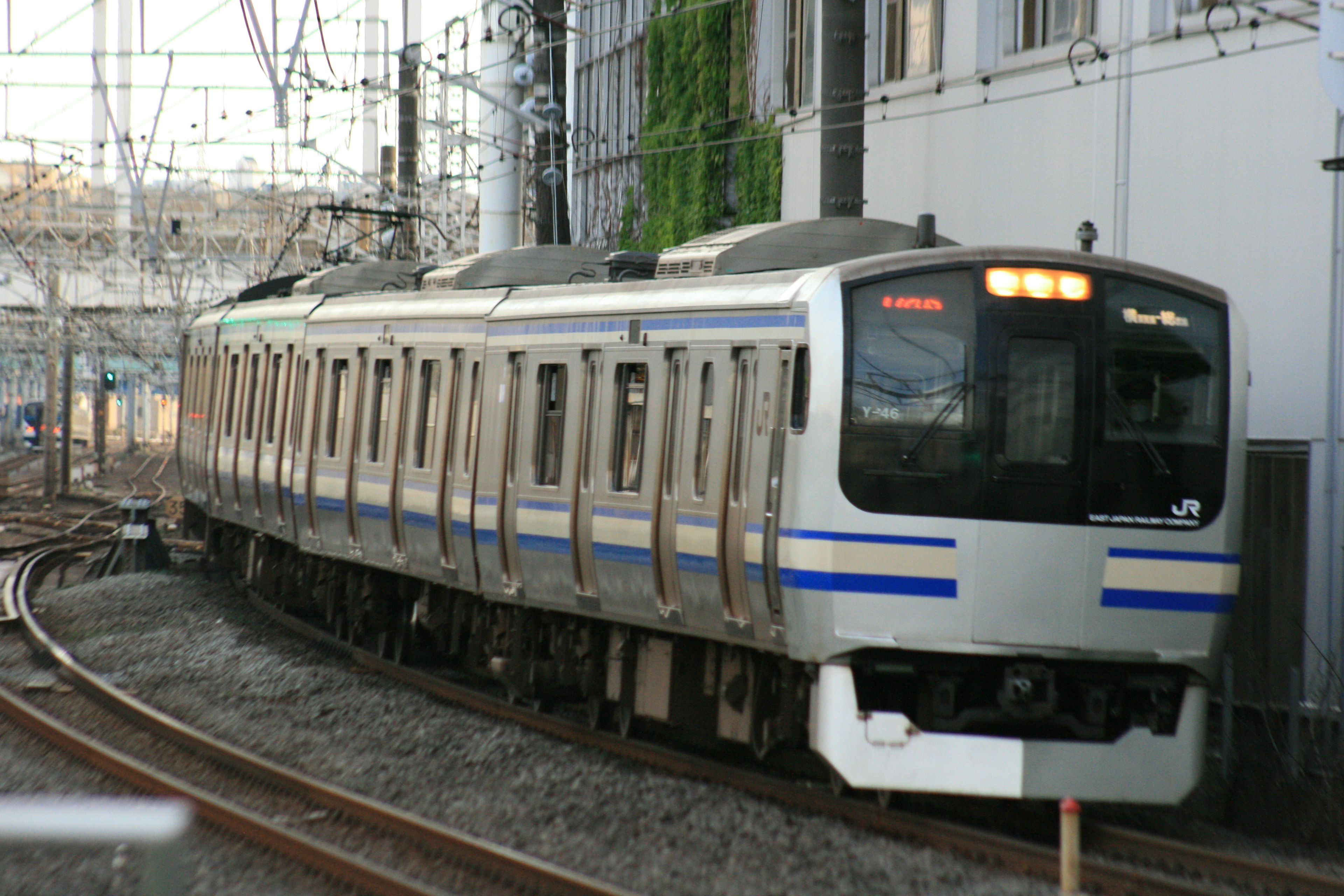 Silver train navigating a curve in an urban setting