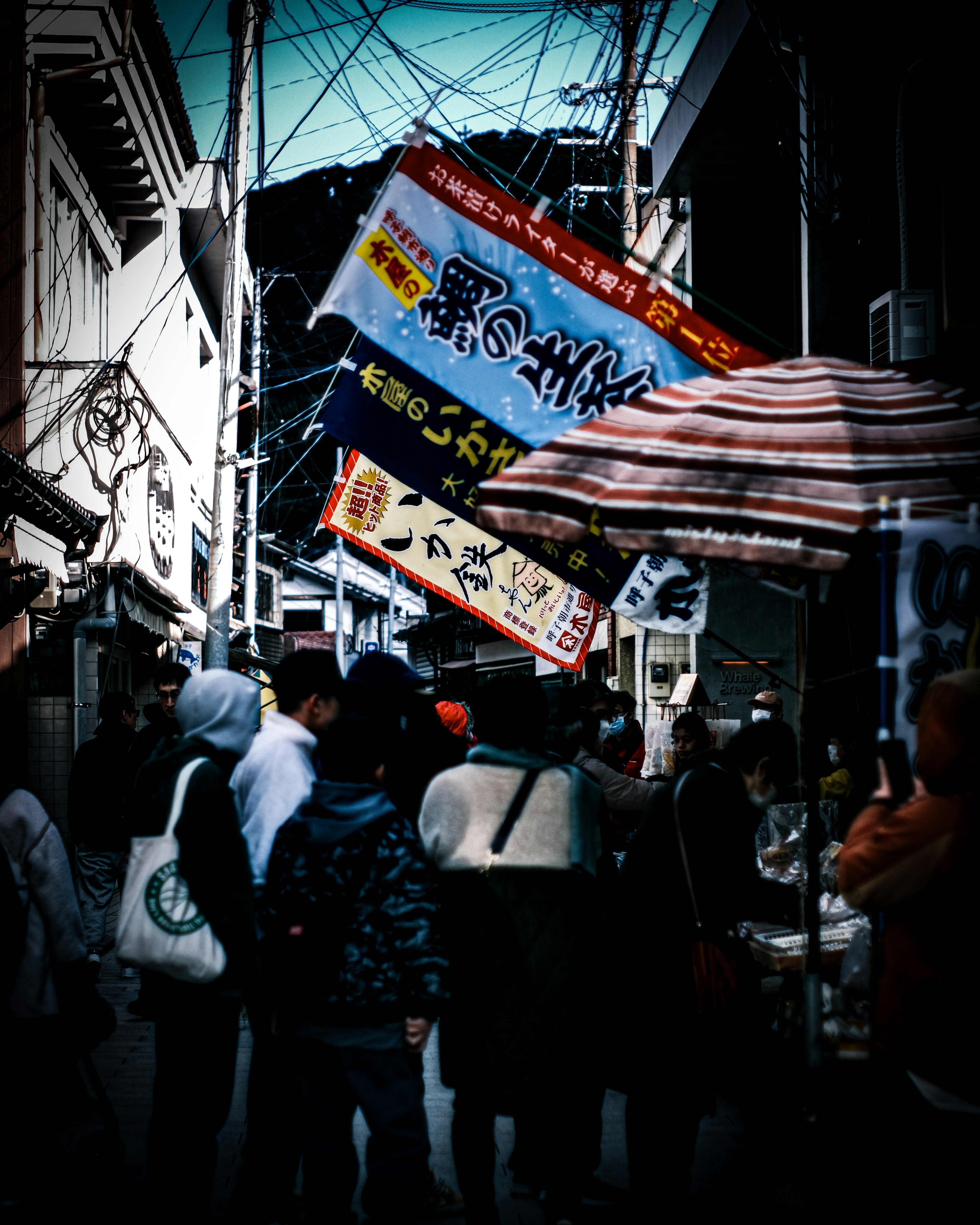 Mercado callejero concurrido con personas y pancartas coloridas colgando