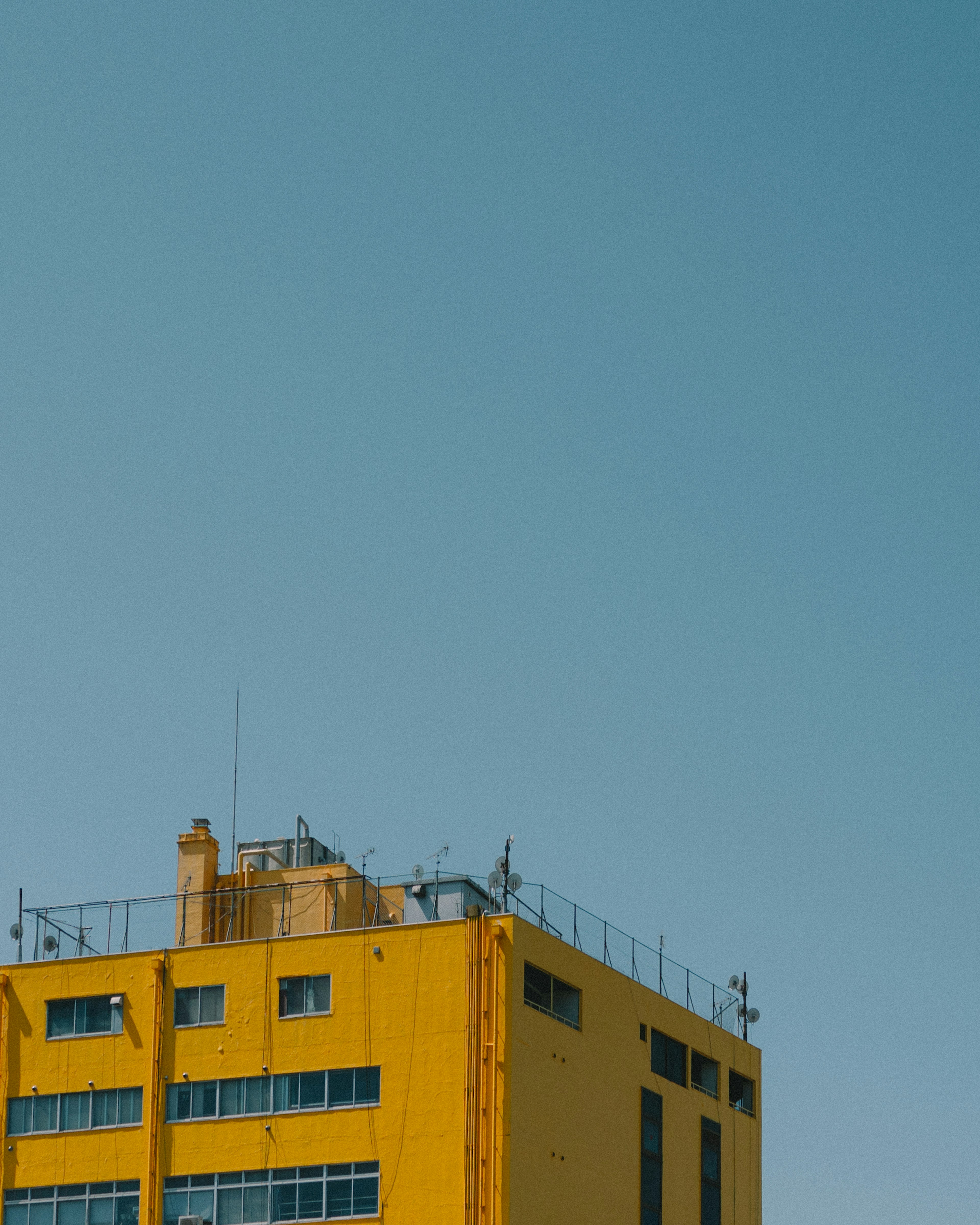 Oberseite eines gelben Gebäudes vor einem klaren blauen Himmel