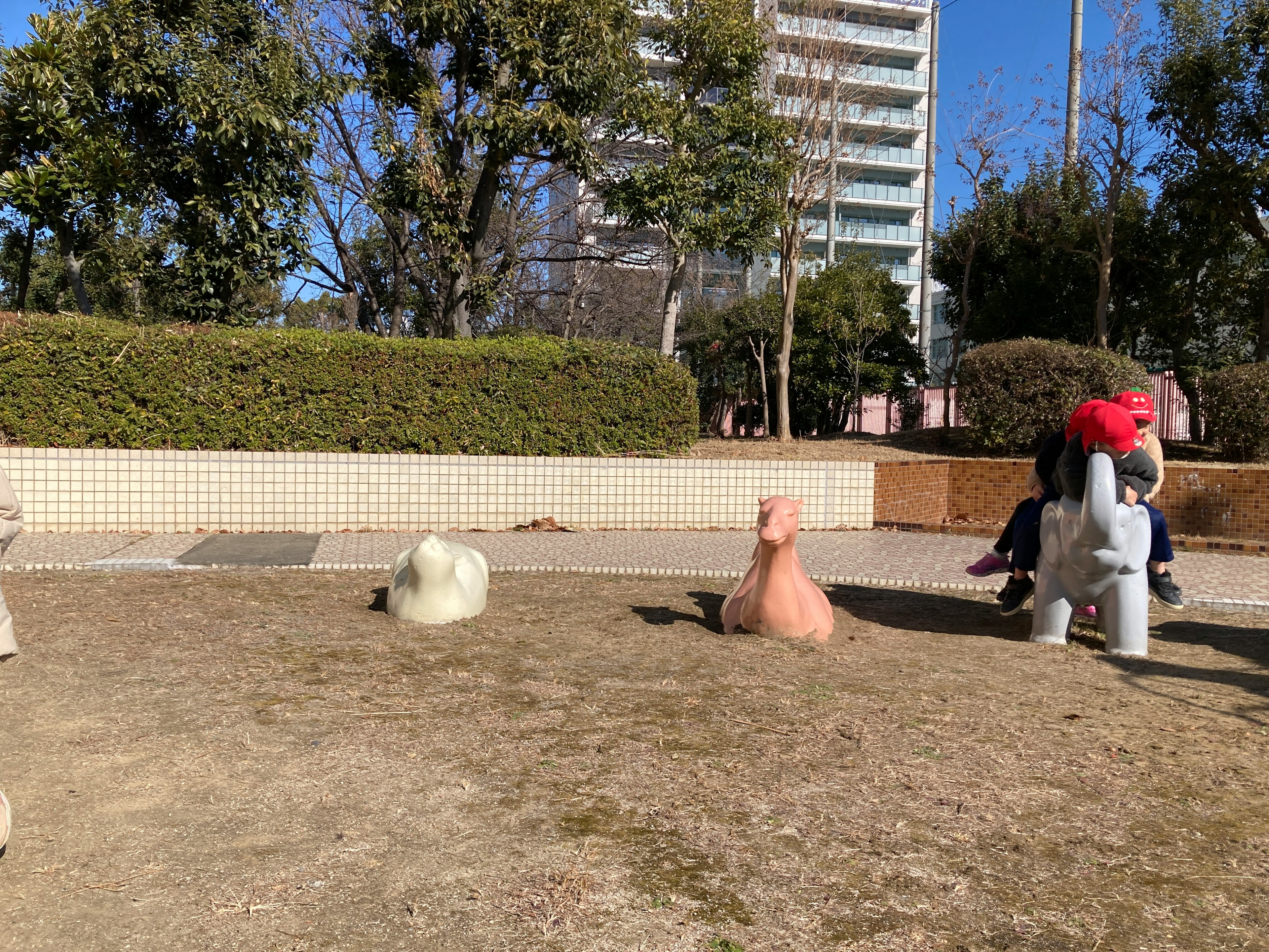 公園の遊び場にある動物の形をした彫刻たちと背後の高層ビル