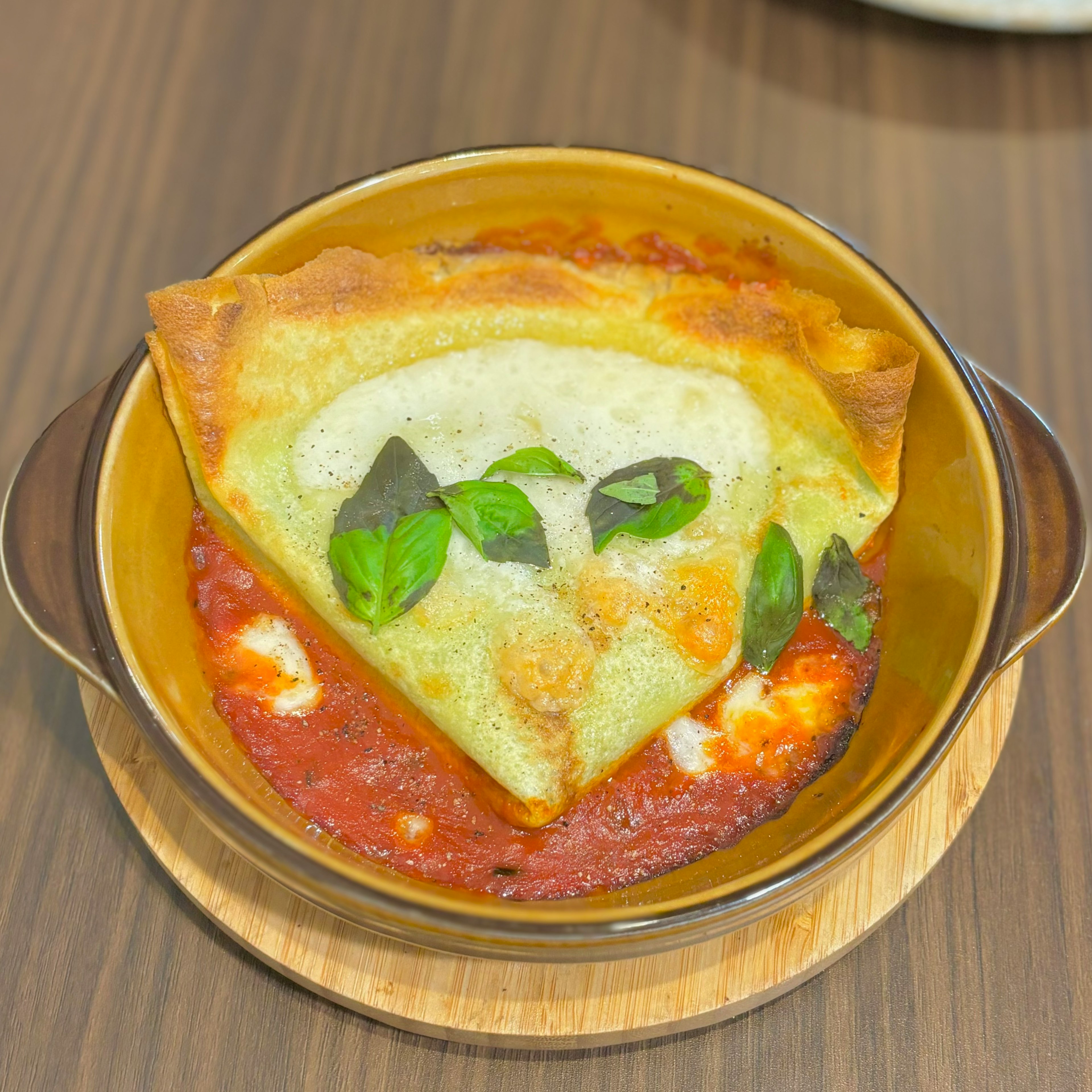 Lasaña al horno servida en un plato decorada con albahaca fresca