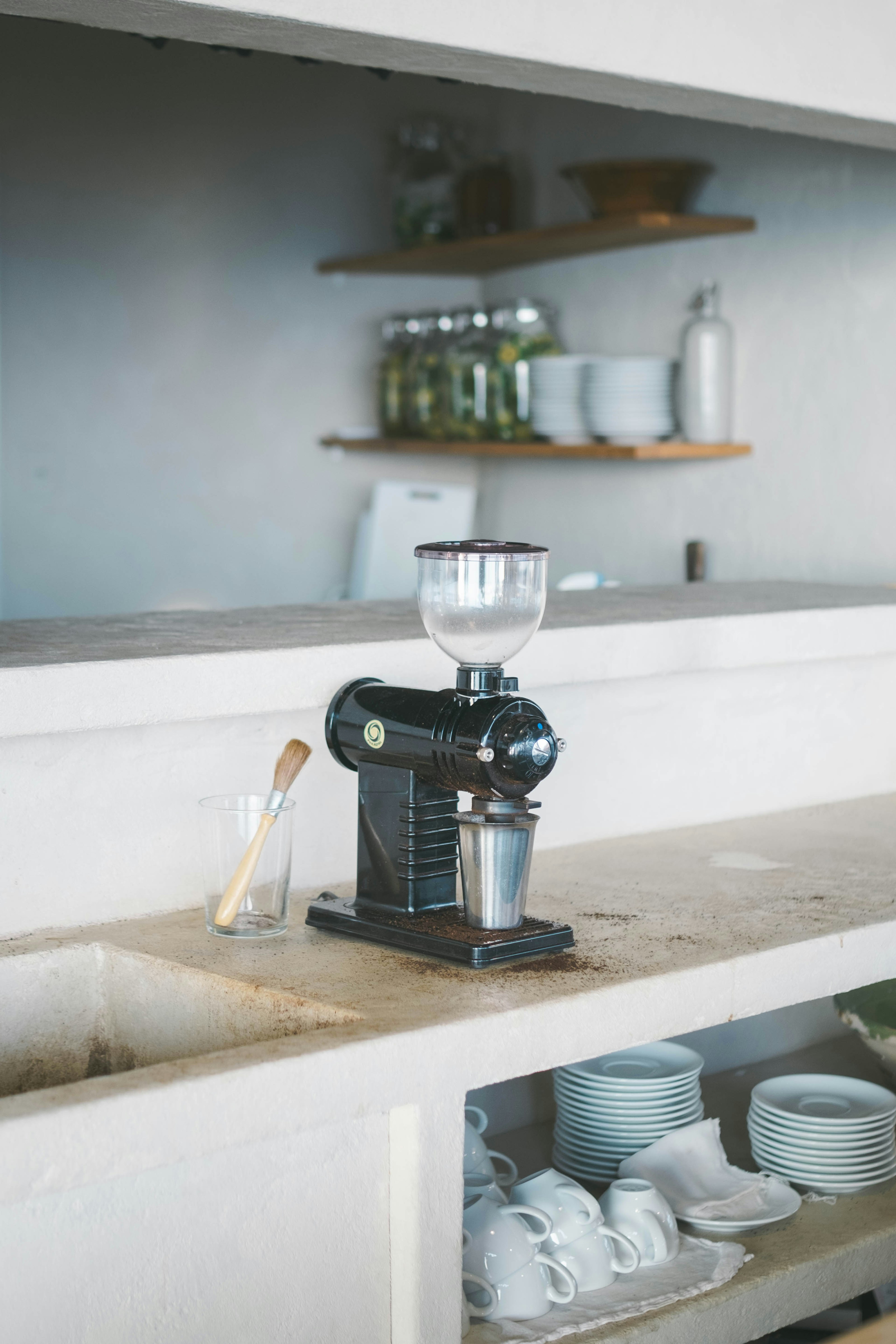 Black coffee grinder on a kitchen countertop with simple dishware