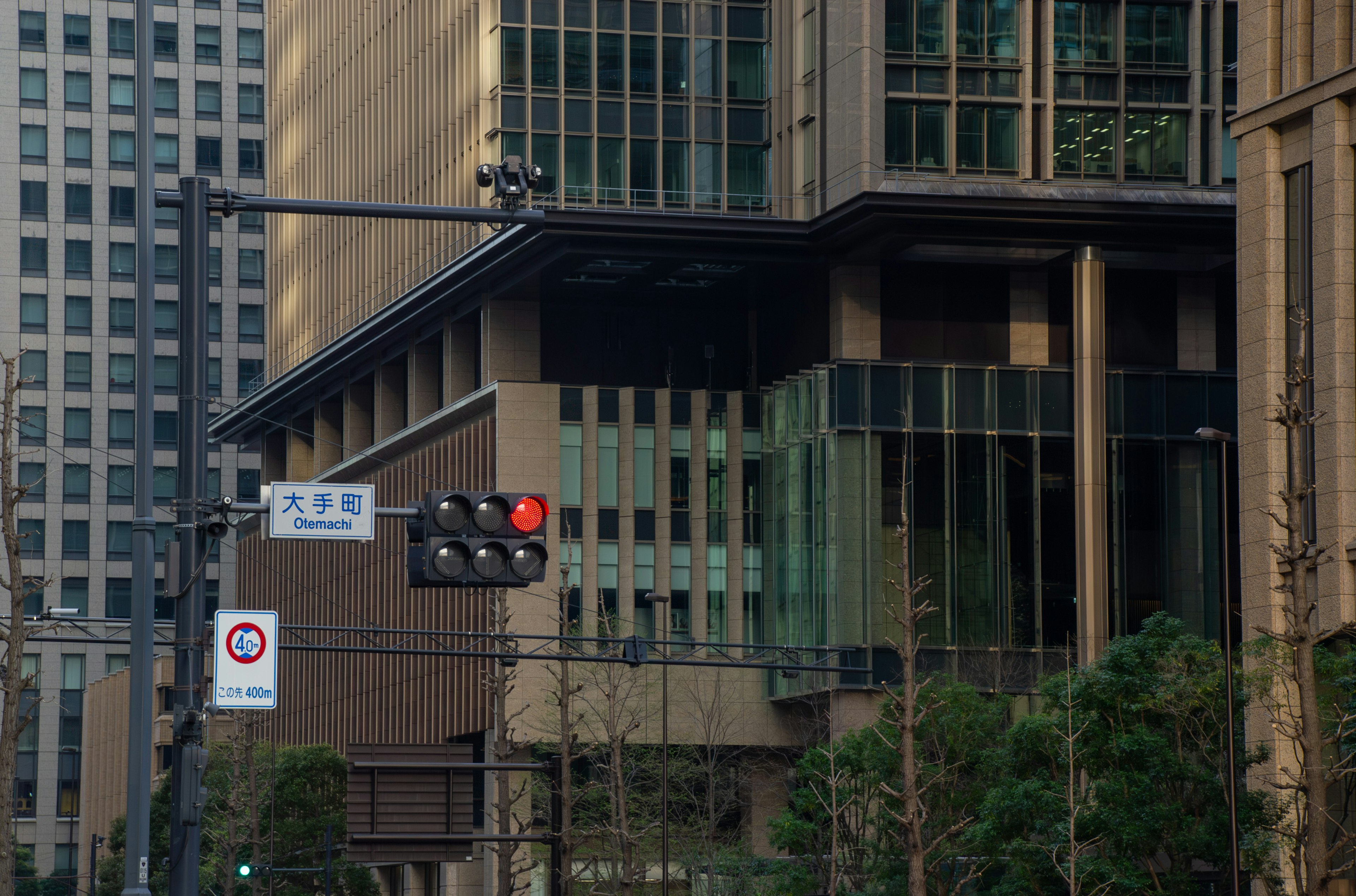 Corner of a modern building with a traffic light and surrounding urban landscape