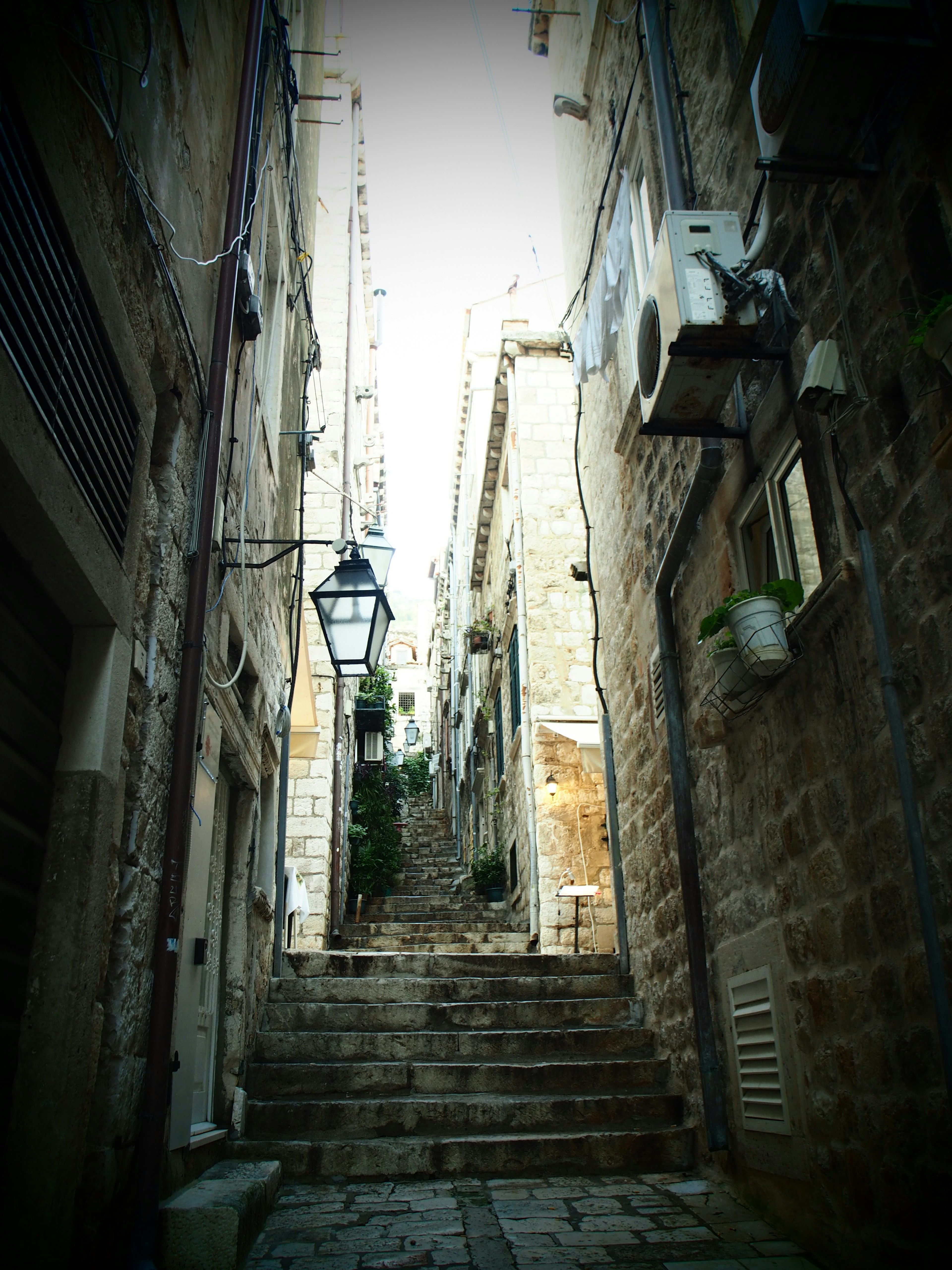 Narrow stone alley with stairs and an old street lamp