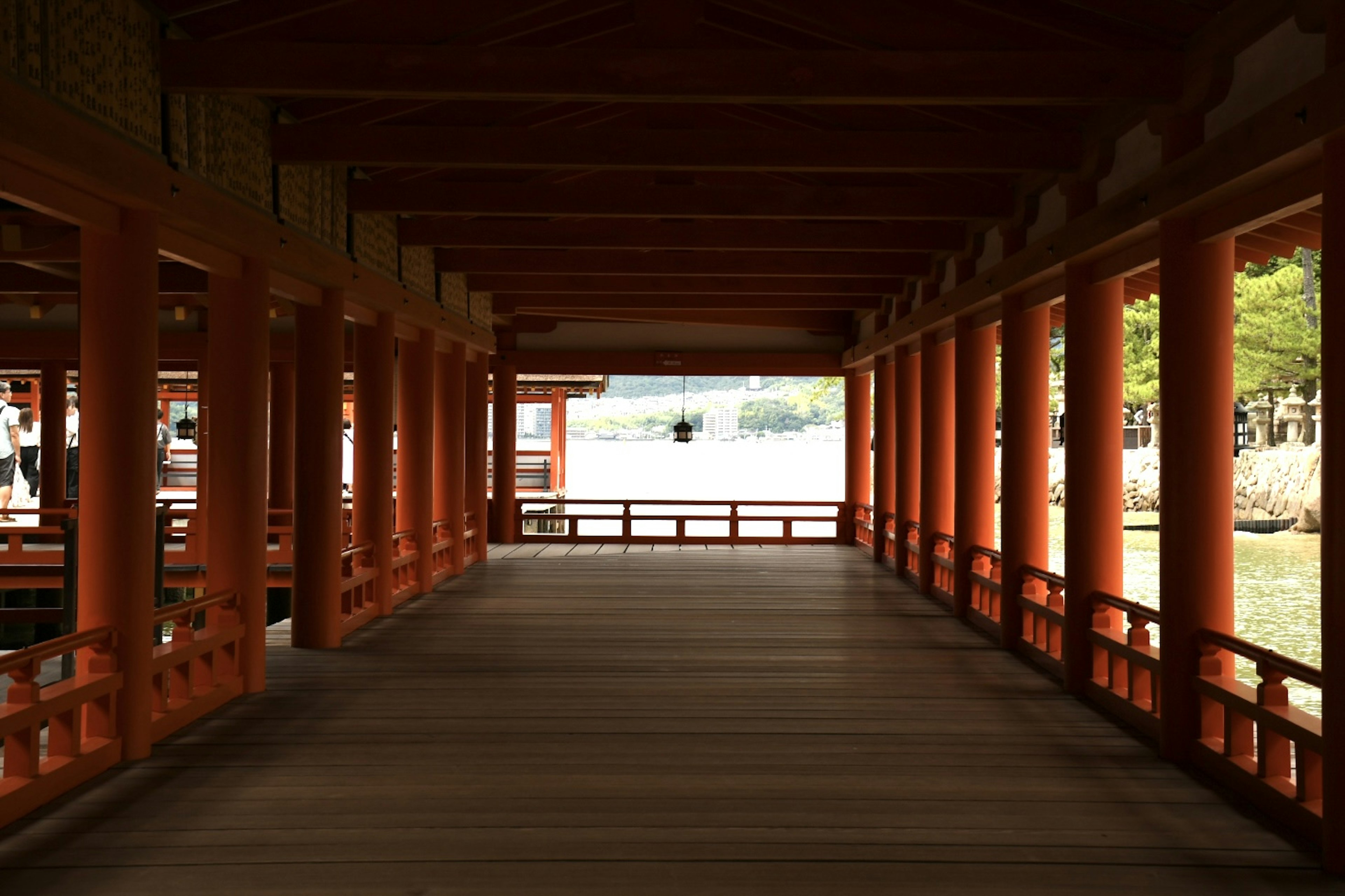 Corridor framed by red pillars with a view of the water