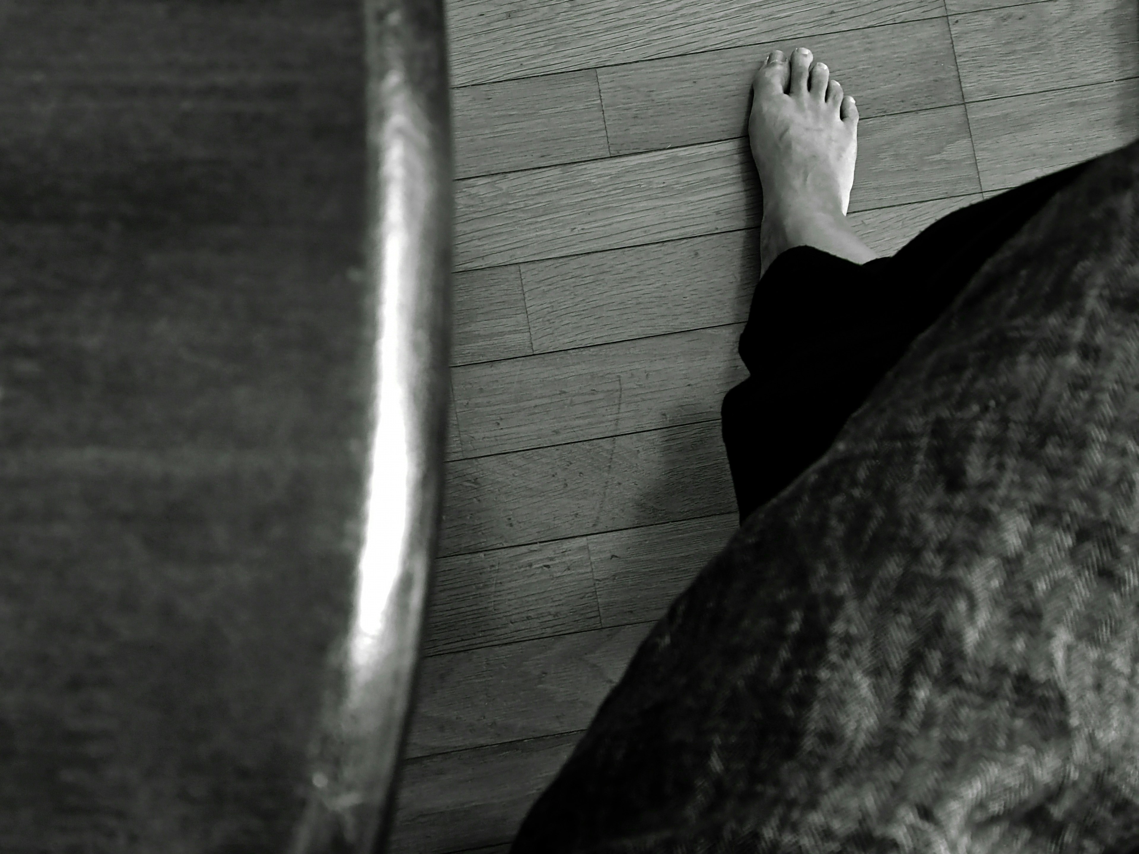 Close-up monochrome photo of a foot and floor