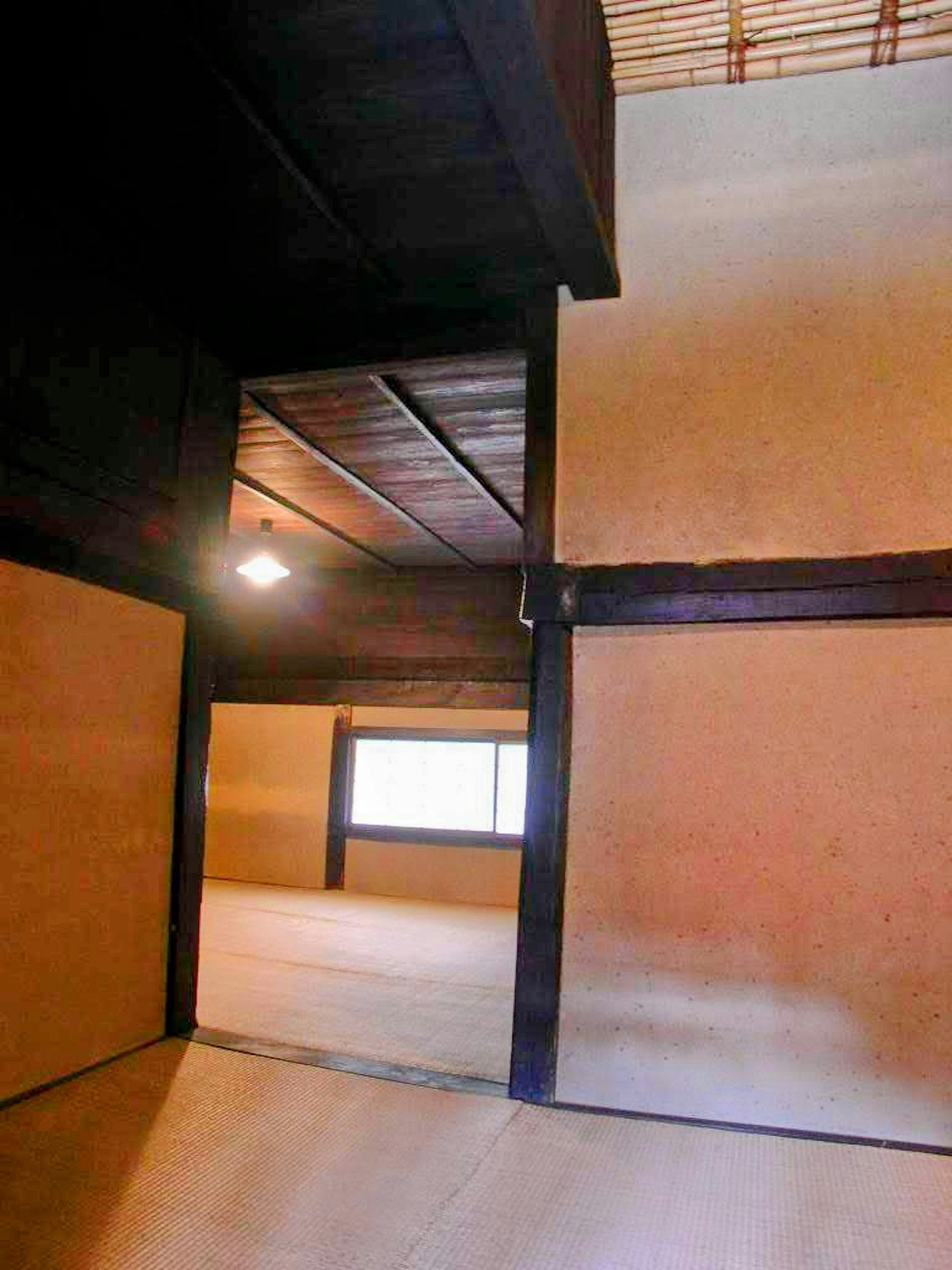 Interior of a traditional Japanese room featuring wooden beams and a bright window