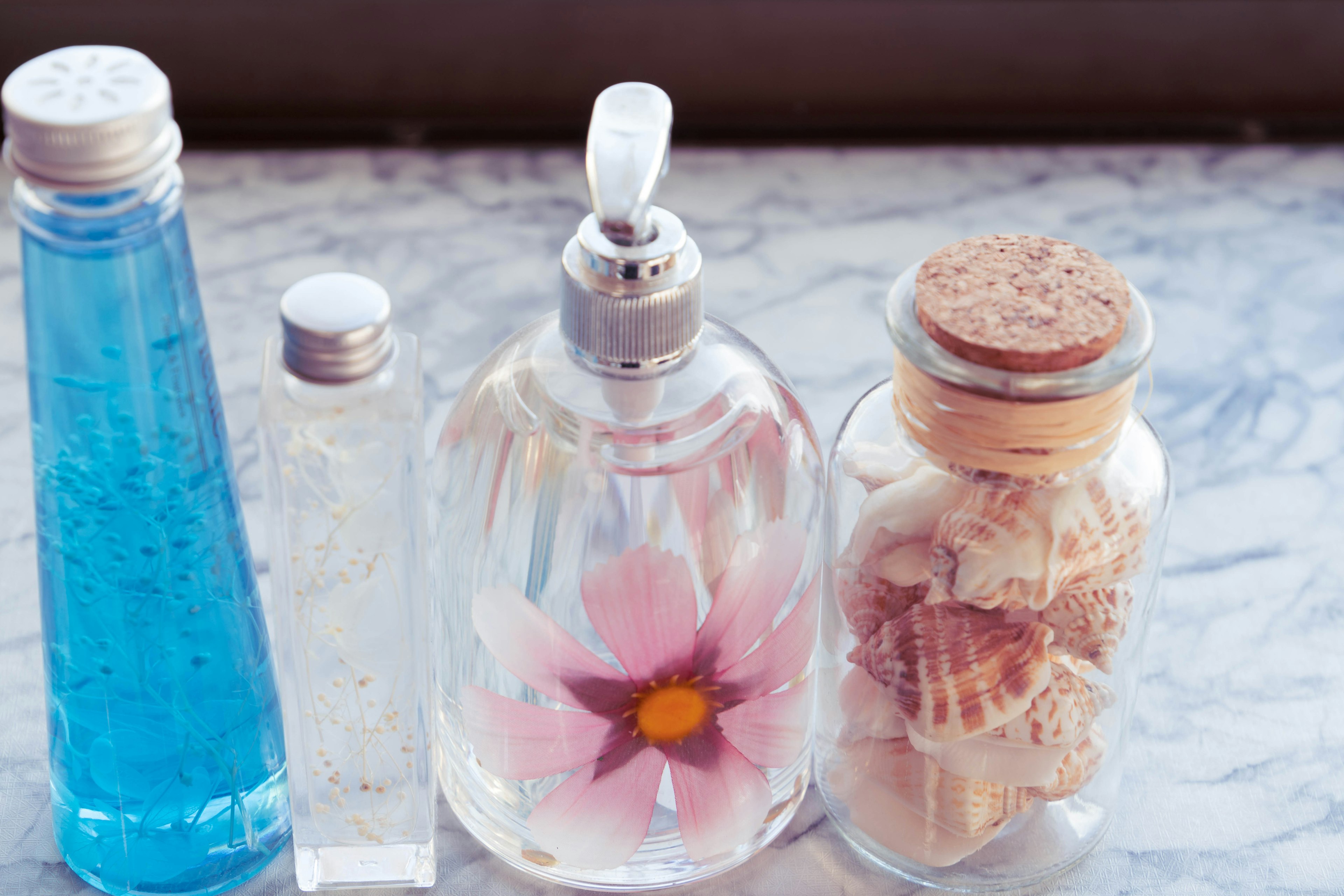 A beautiful still life featuring a blue liquid bottle and a perfume bottle with a flower inside