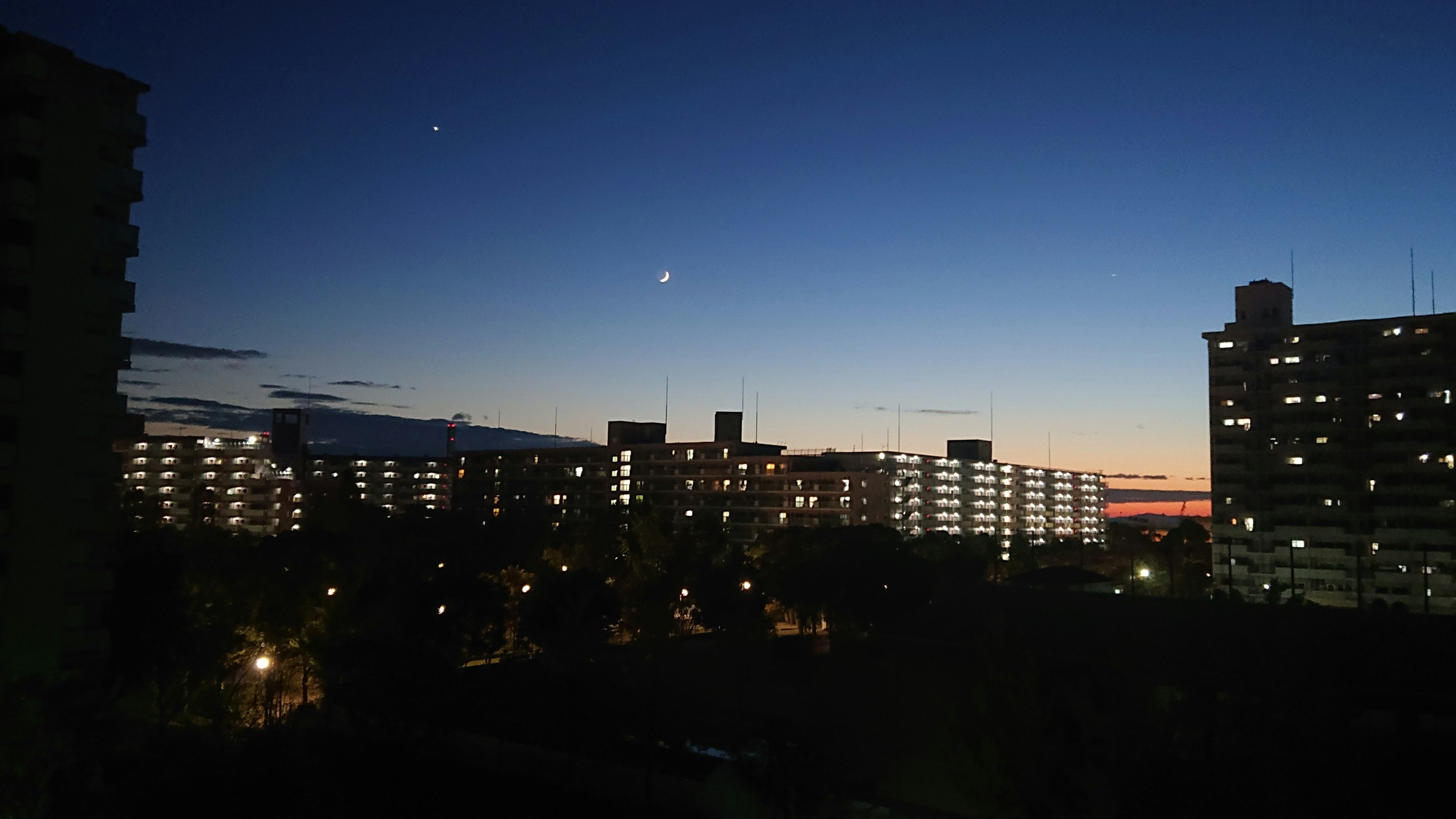 夜空に輝く星と月が見える都市の風景