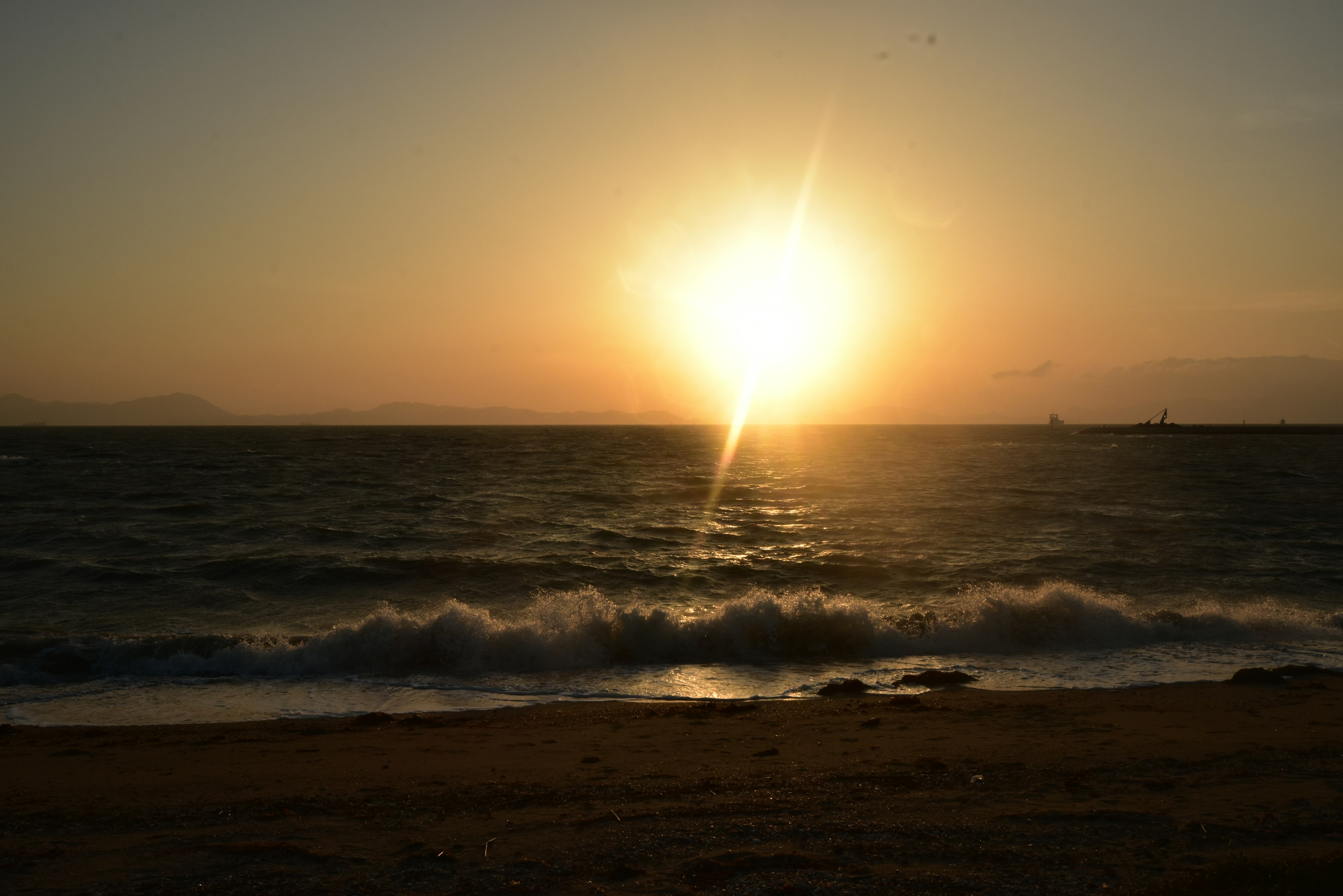 夕日が海に沈む美しい風景波が砂浜に打ち寄せる