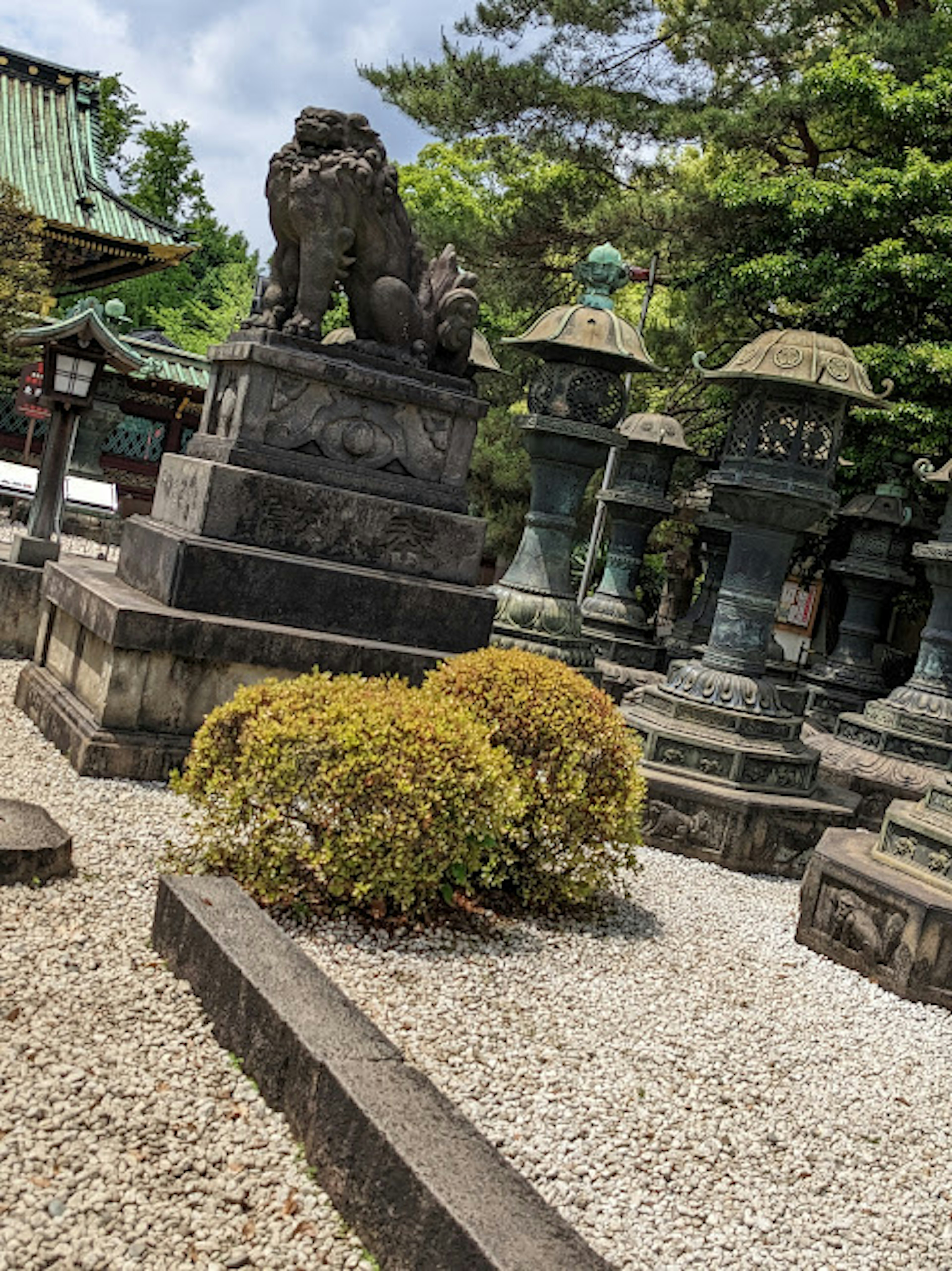 A landscape featuring a stone lion statue and lanterns in a cemetery