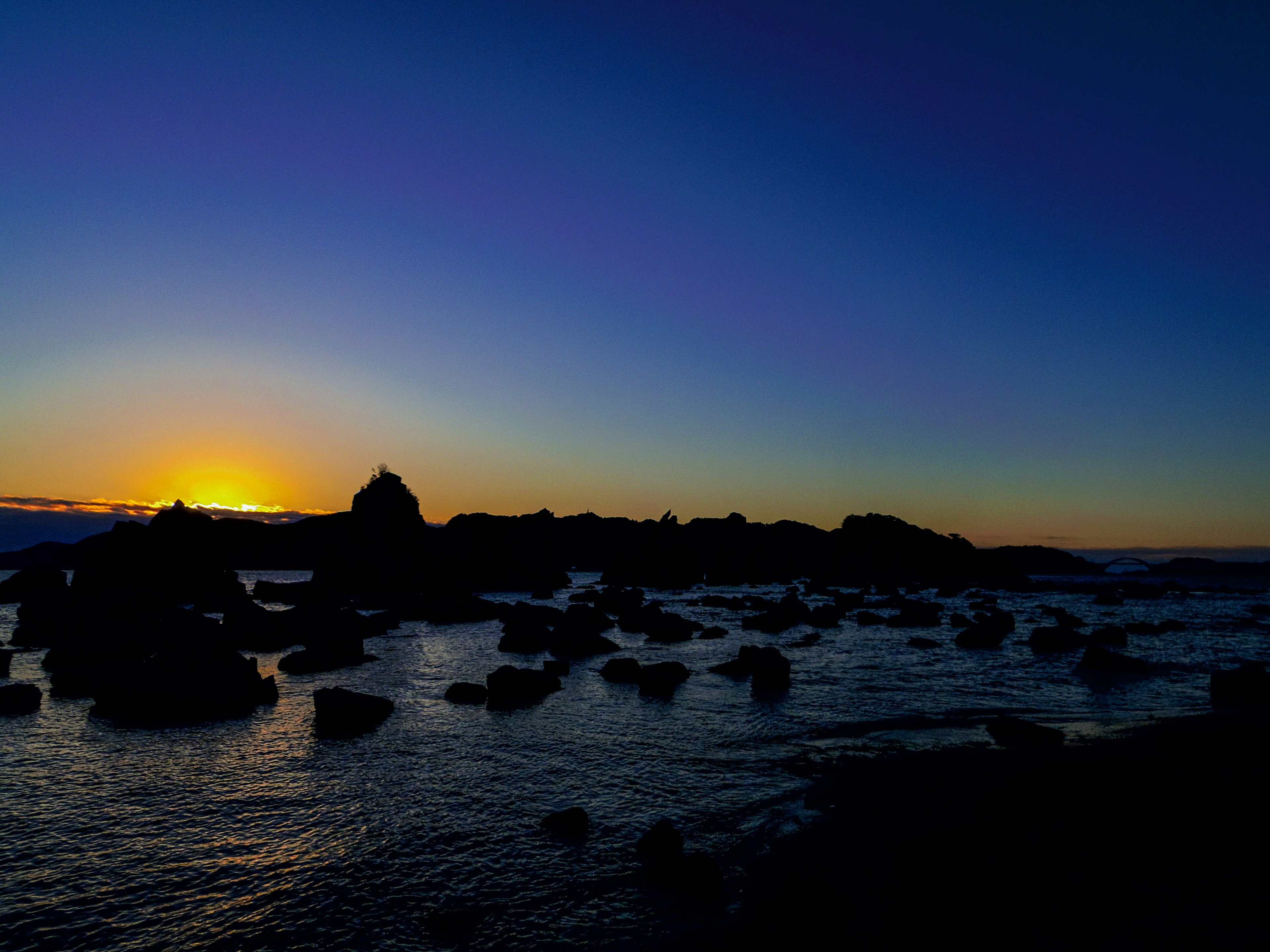 Bella scena costiera con rocce e un tramonto luminoso