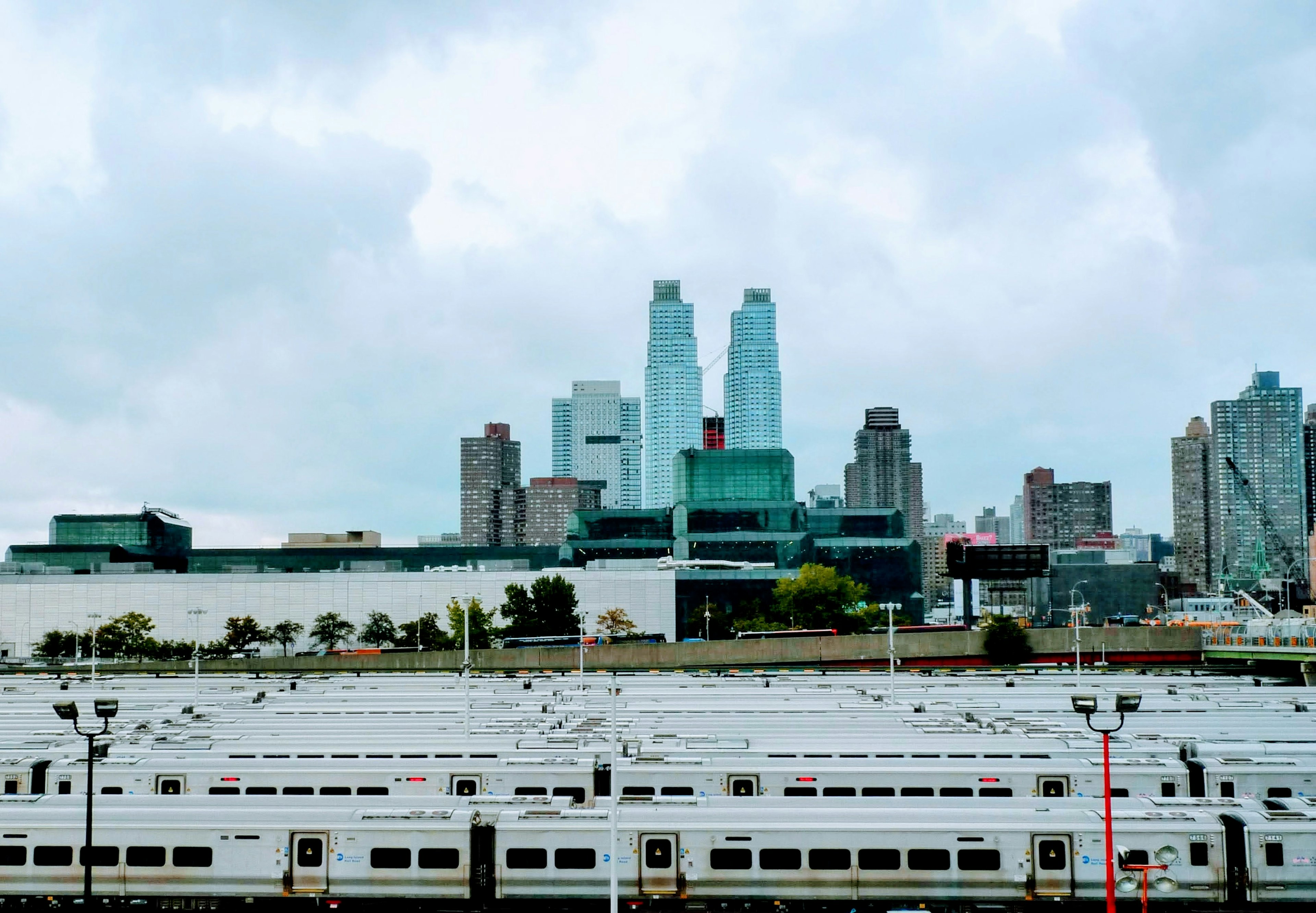 Urban skyline under cloudy sky with rows of train cars