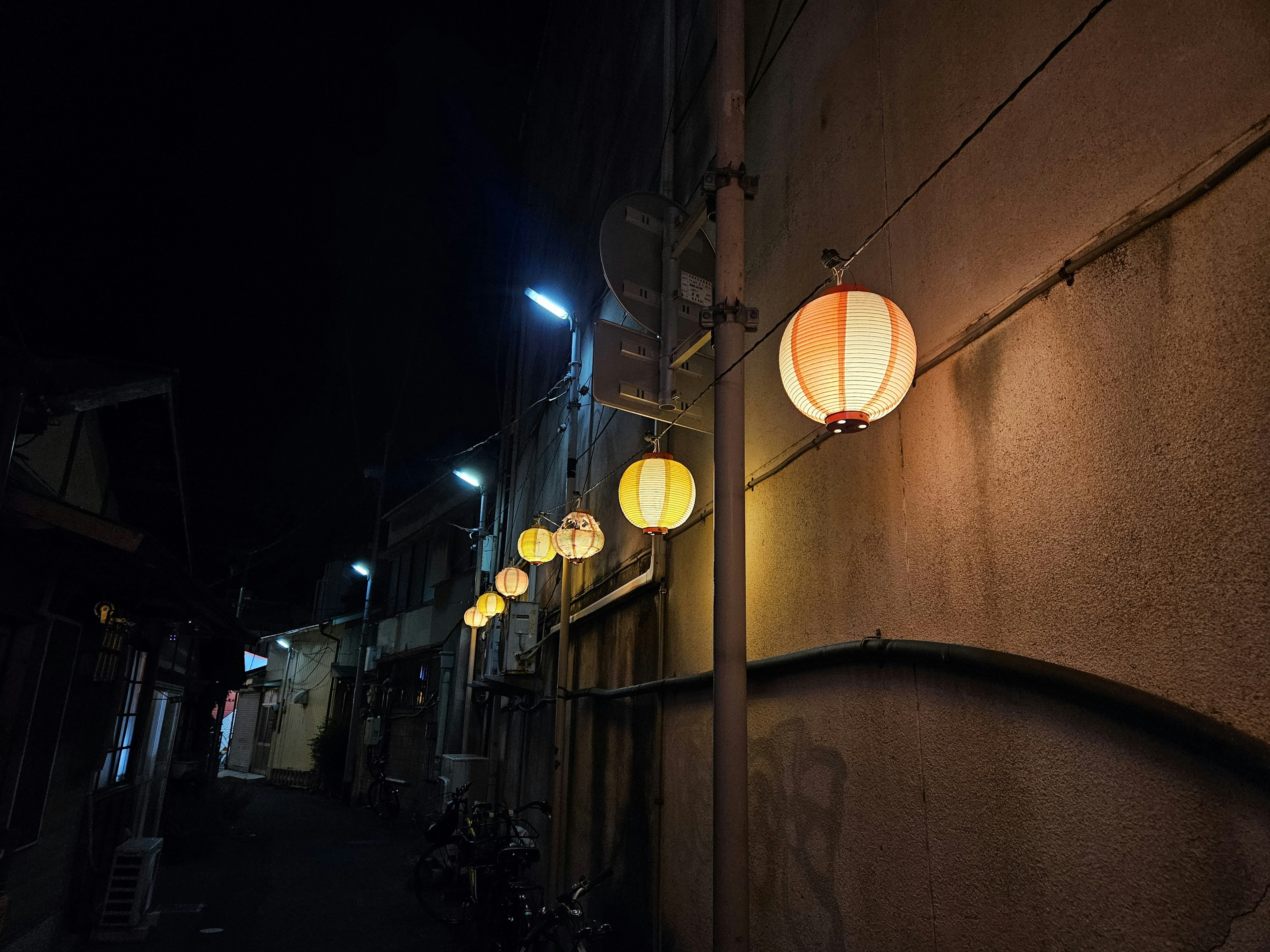 Rangée de lanternes illuminant une ruelle étroite la nuit avec des bâtiments anciens