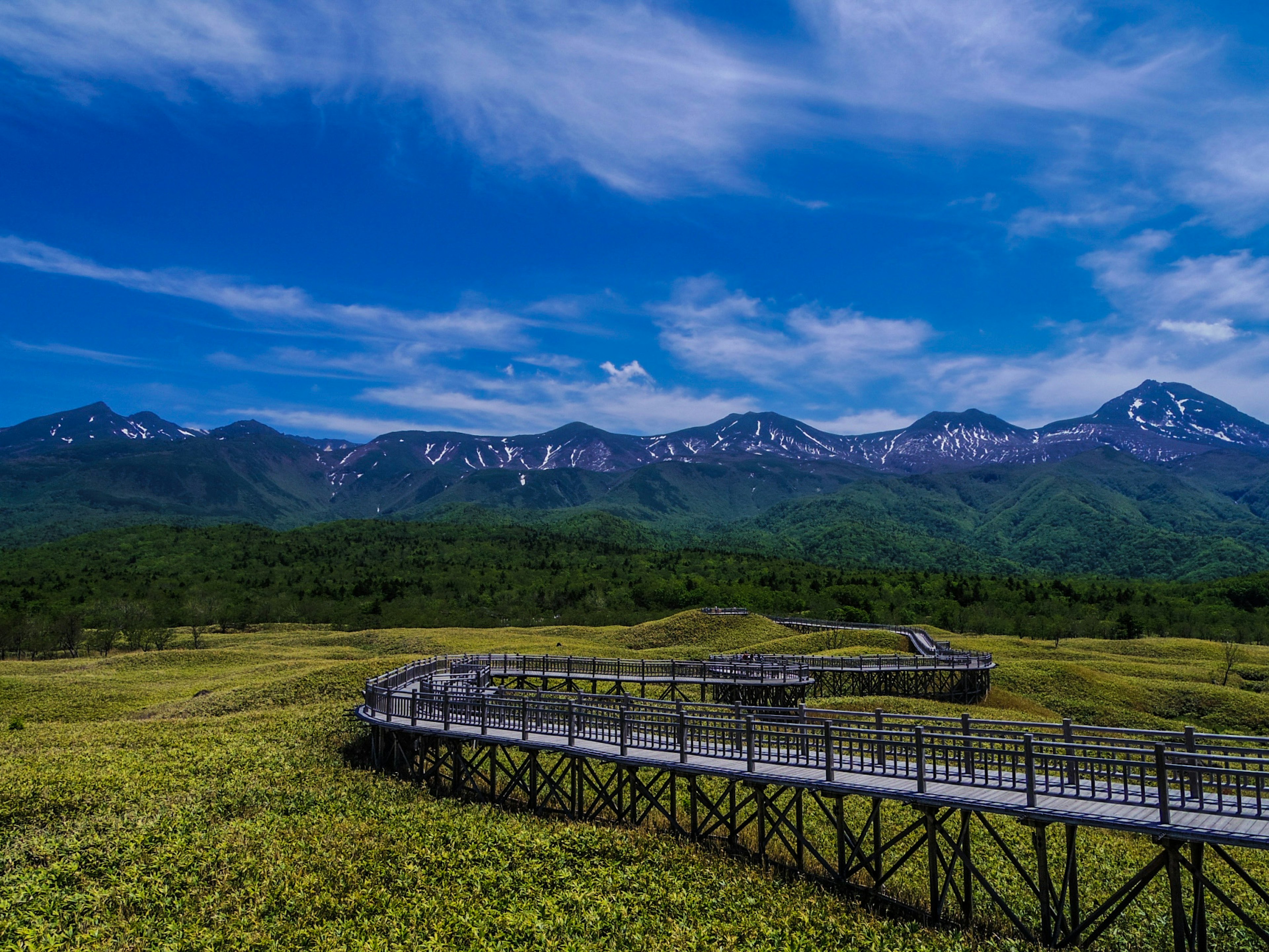 Passerelle en bois courbée avec de belles montagnes et un ciel bleu en arrière-plan